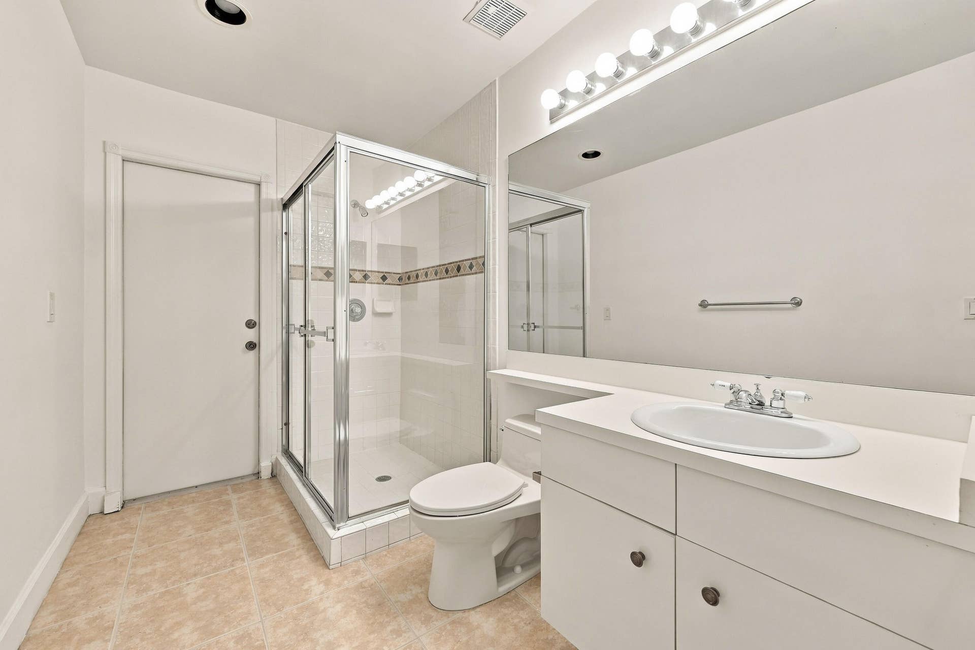 10671 St Thomas Drive, Boca Raton, FL 33498 This well-appointed full bathroom features a spacious vanity, large mirror, glass-enclosed shower, and convenient access from the main living areas and guest bedroom.