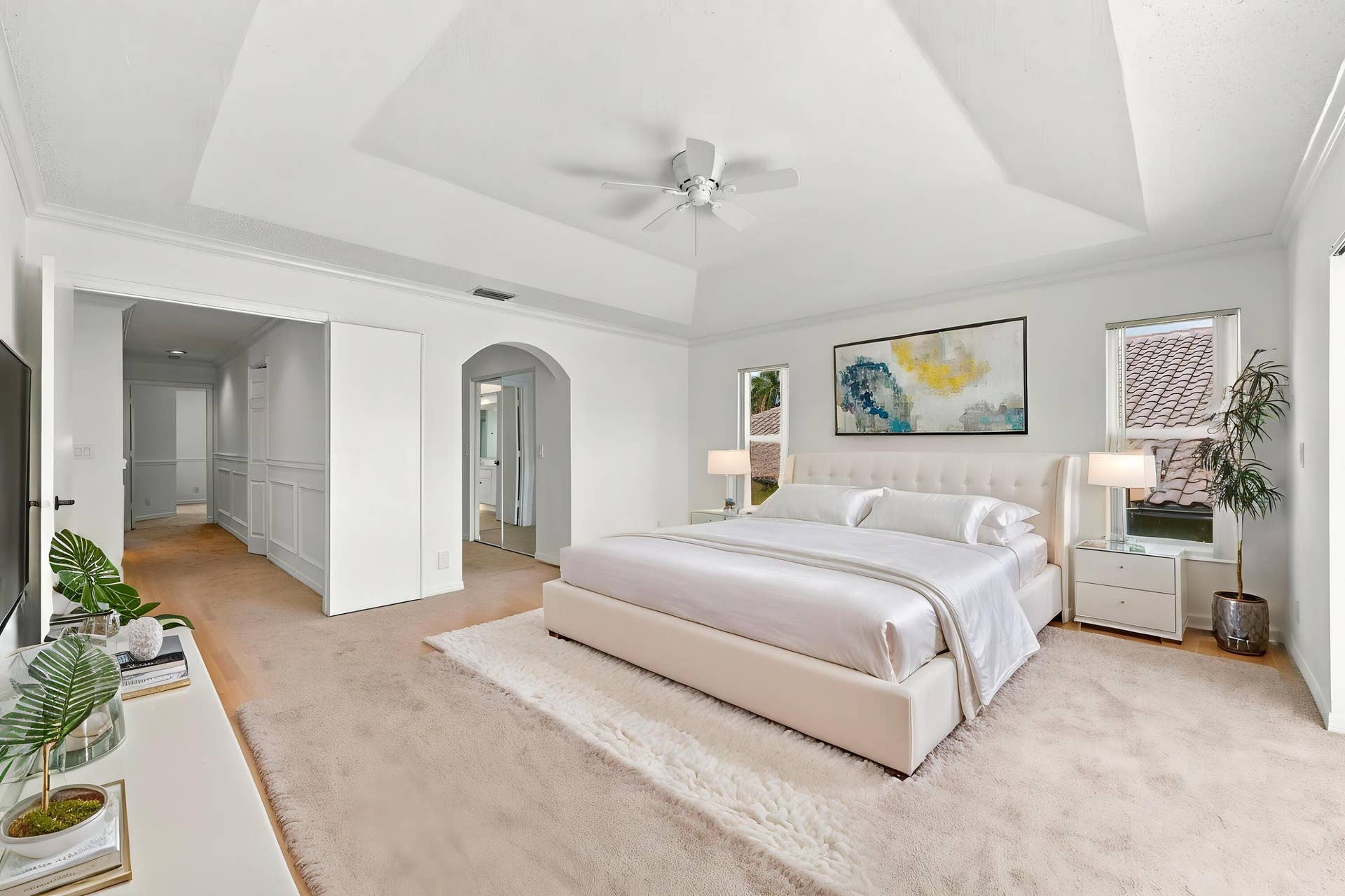 10671 St Thomas Drive, Boca Raton, FL 33498 An impressive primary bedroom featuring a decorative tray ceiling, generous proportions, and a private entrance to the adjoining bathroom and dressing areas.