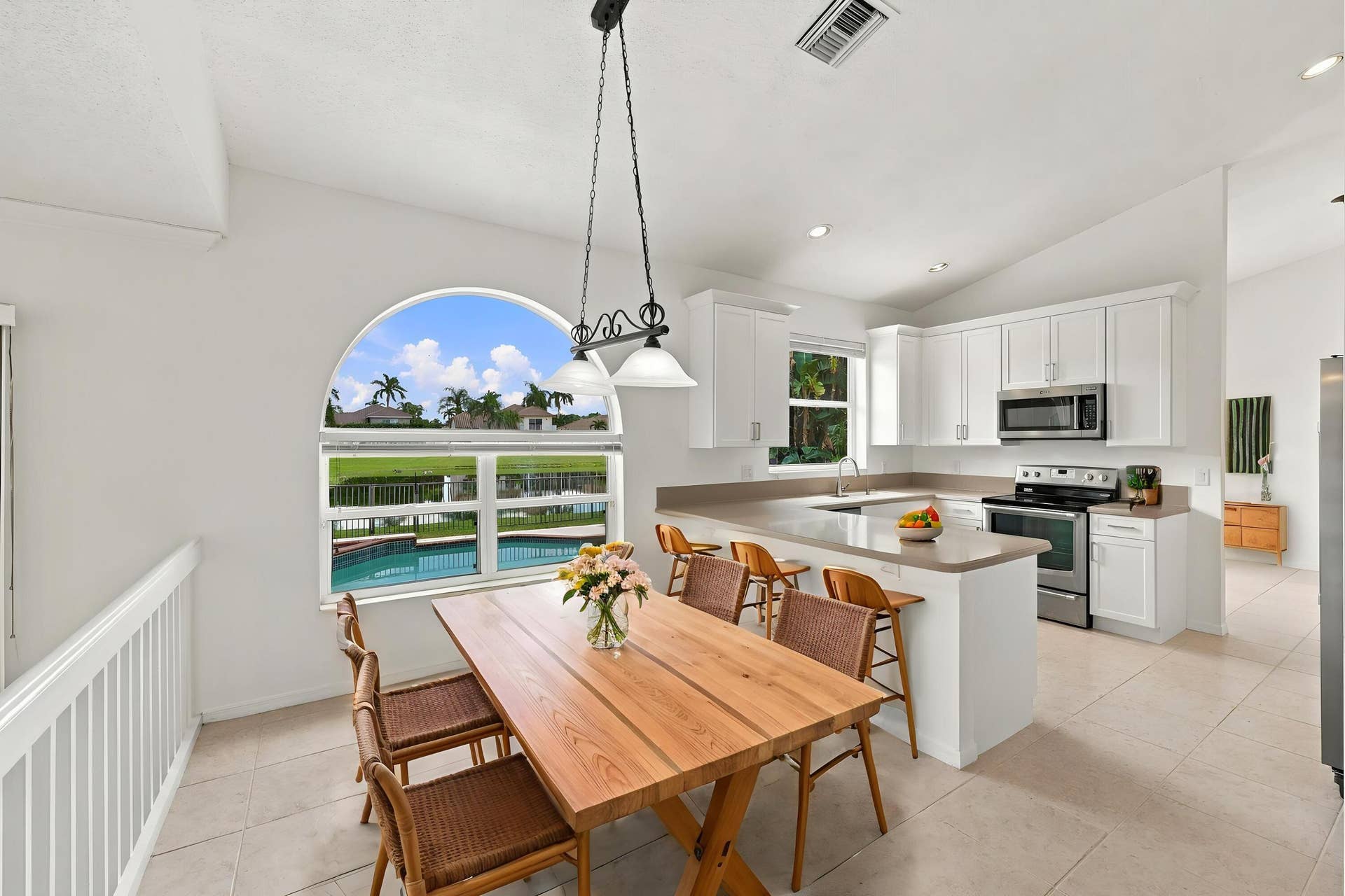 10671 St Thomas Drive, Boca Raton, FL 33498 Enjoy picturesque views of the surrounding greenery from the charming breakfast nook, complete with an oversized arched window, vaulted ceilings, and decorative lighting.
