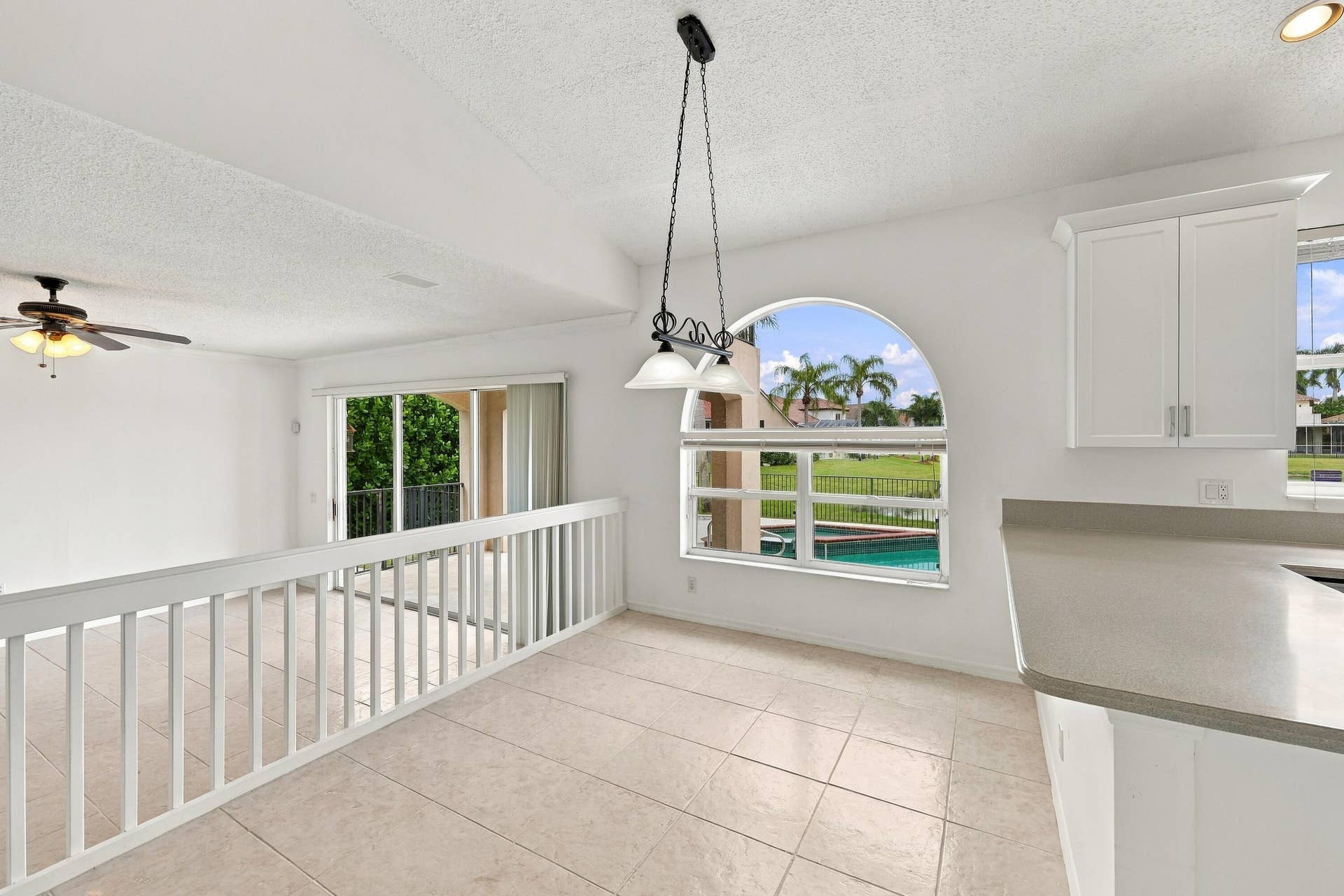 10671 St Thomas Drive, Boca Raton, FL 33498 A wonderful setting for casual dining, this breakfast nook features an oversized arched window, decorative pendant lighting, and an open connection to the adjacent family room.