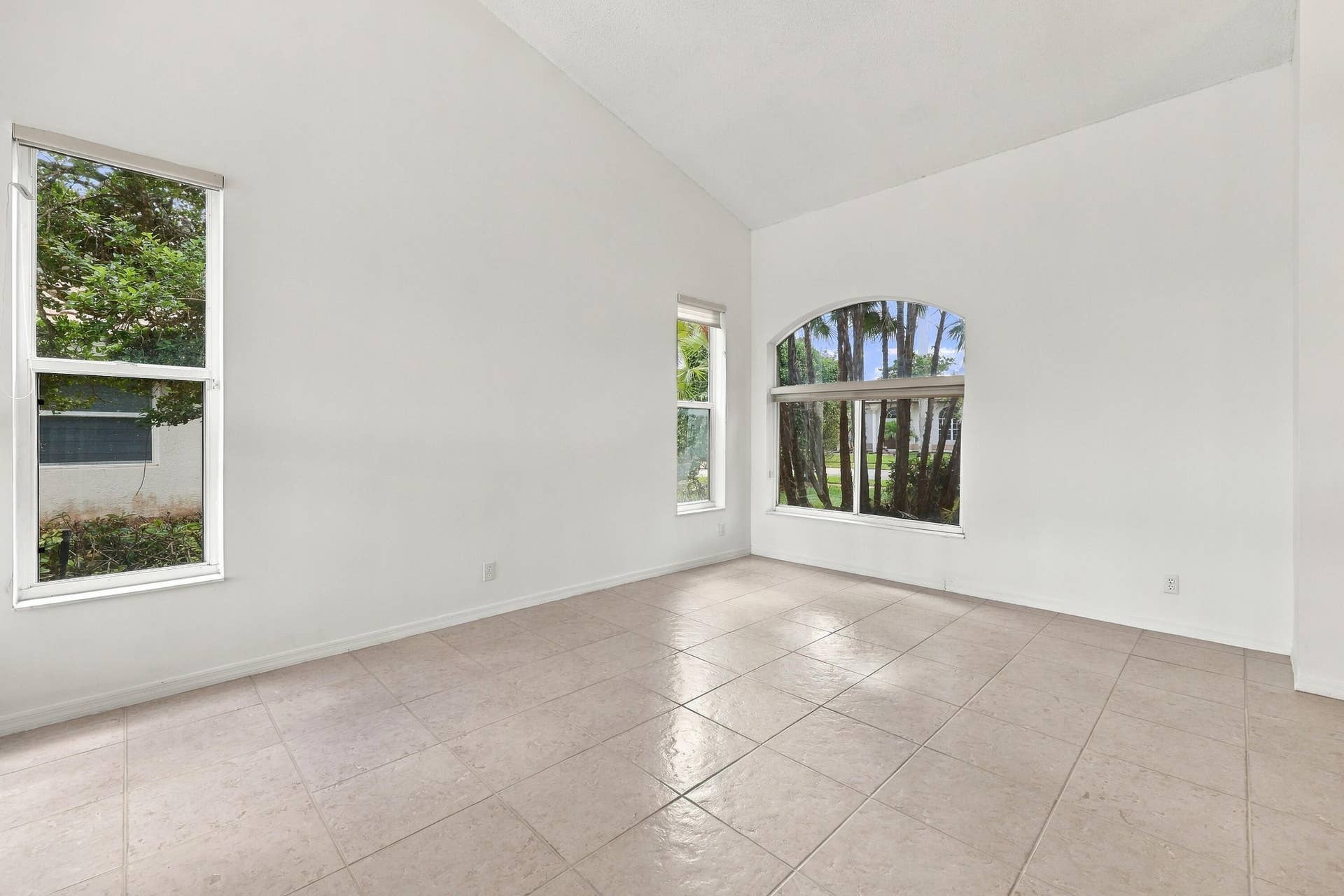 10671 St Thomas Drive, Boca Raton, FL 33498 Soaring vaulted ceilings, expansive windows, and abundant natural light create a bright, inviting formal living room with an impressive sense of space.