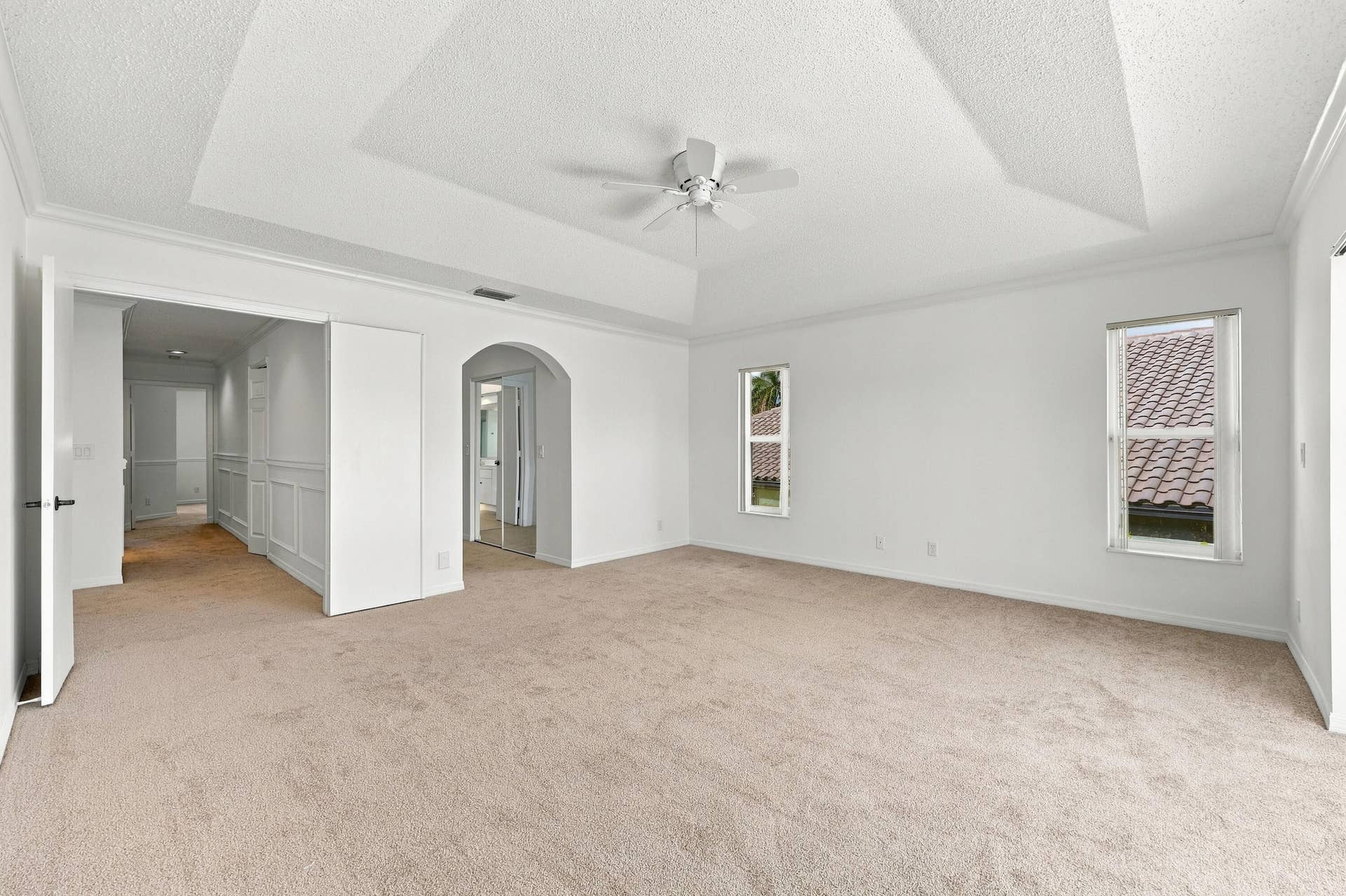 10671 St Thomas Drive, Boca Raton, FL 33498 An impressive primary bedroom featuring a decorative tray ceiling, generous proportions, and a private entrance to the adjoining bathroom and dressing areas.