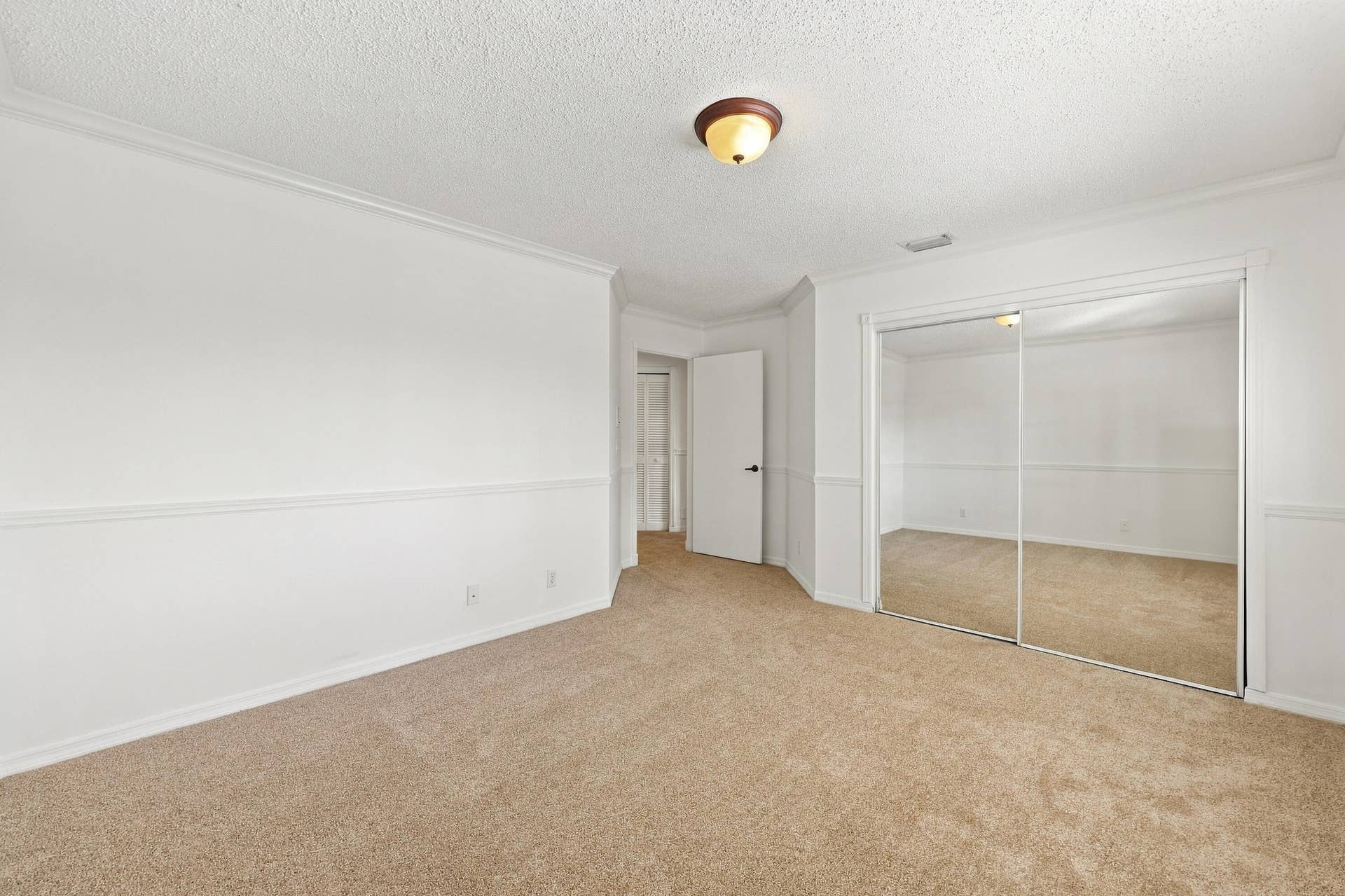 10671 St Thomas Drive, Boca Raton, FL 33498 An inviting third bedroom offering a large mirrored closet, neutral finishes, and ample space for comfortable living.