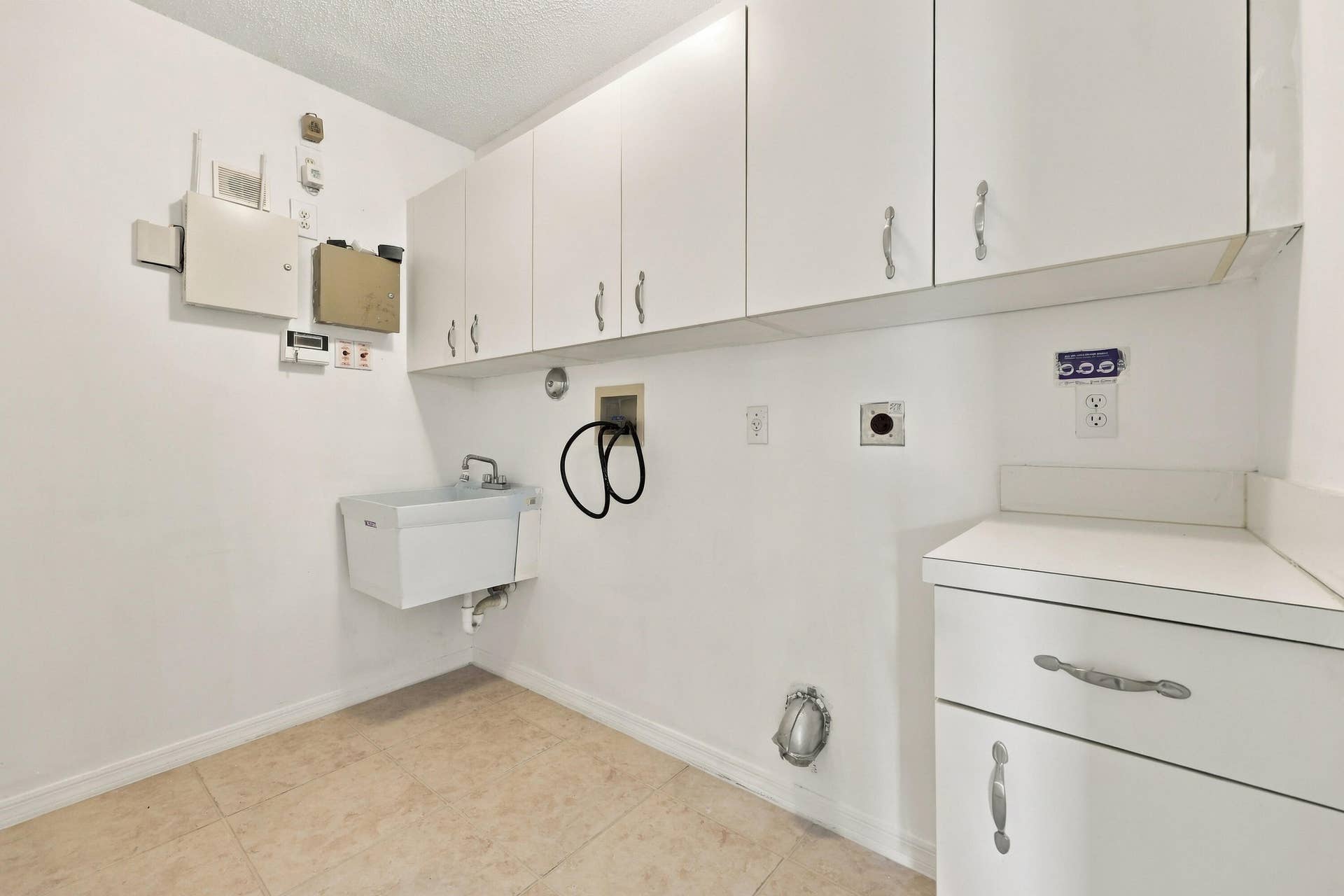10671 St Thomas Drive, Boca Raton, FL 33498 Conveniently located on the first floor, this dedicated laundry room features abundant overhead cabinetry, a utility sink, neutral tile flooring, and plenty of space for laundry appliances and household storage.