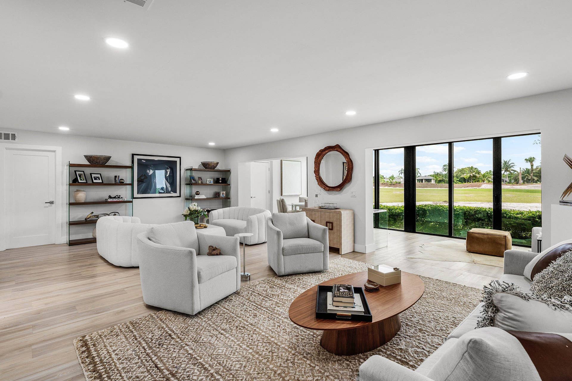 Open-concept space featuring light-toned wood-finish flooring, recessed lighting, built-in shelving, and floor-to-ceiling windows