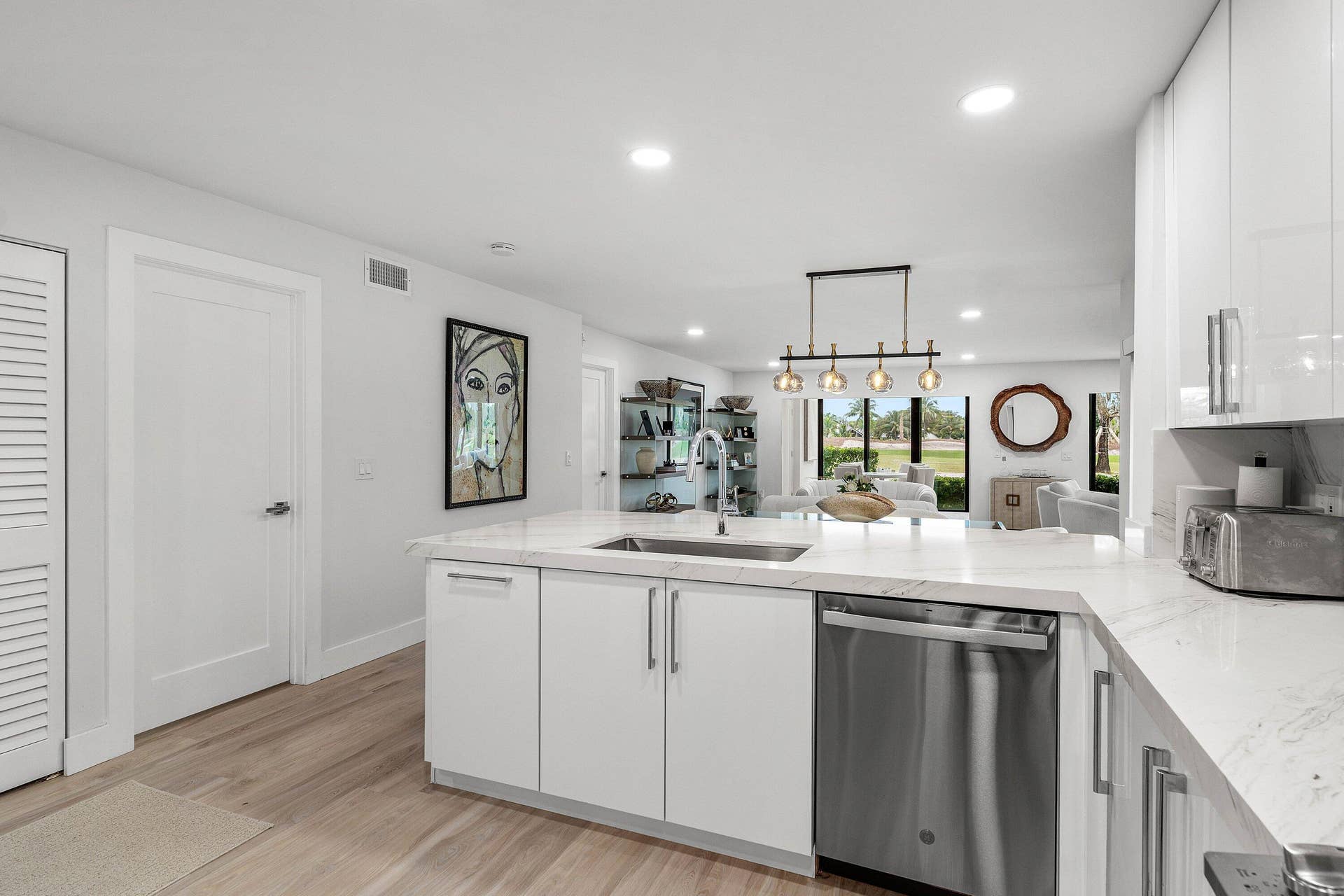 Kitchen featuring white cabinetry, stone-finish countertops, stainless steel dishwasher, integrated sink faucet, and wood-finish flooring