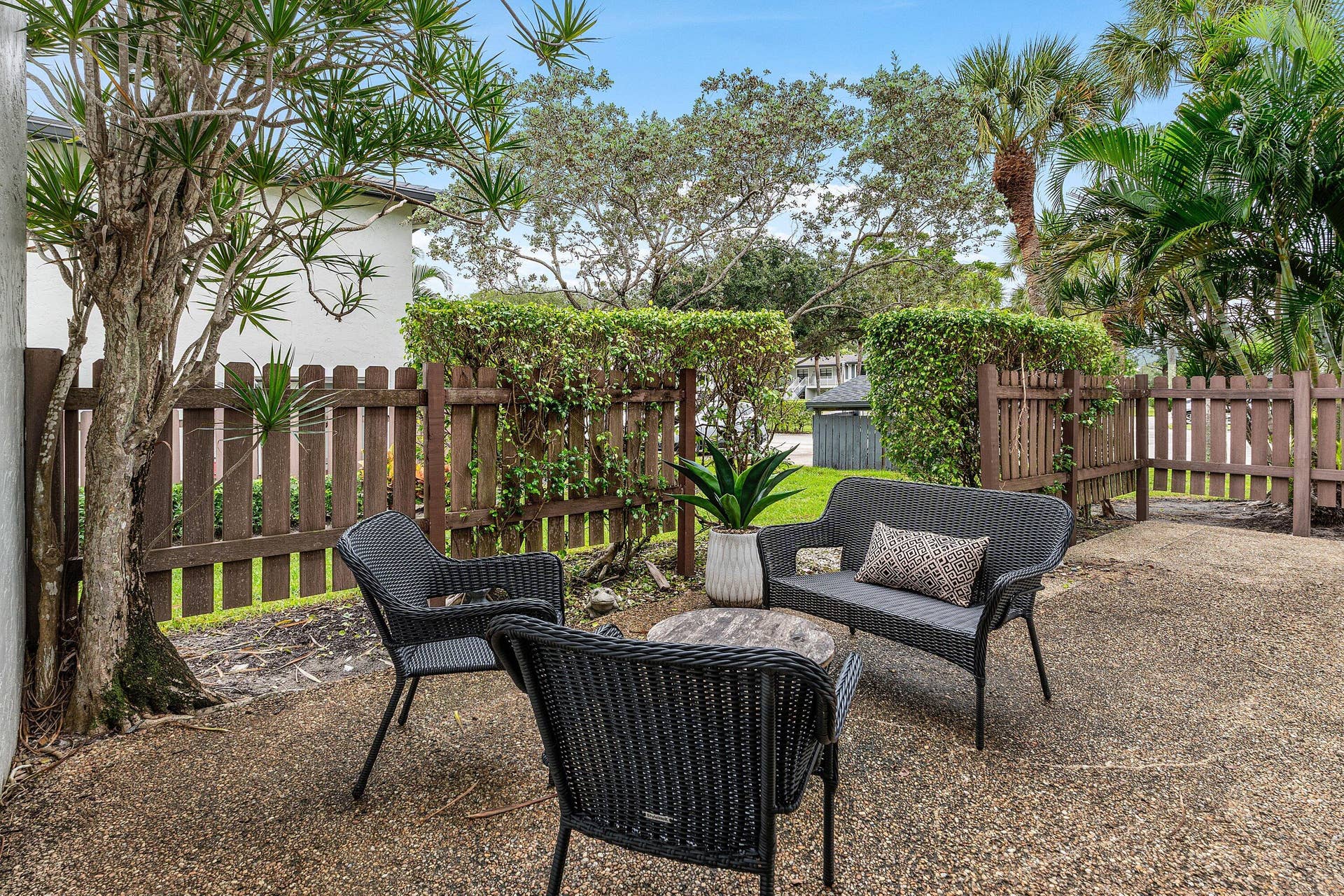 Private rear patio featuring a textured concrete surface, enclosed by a wood-slat privacy fence and established perimeter shrubbery