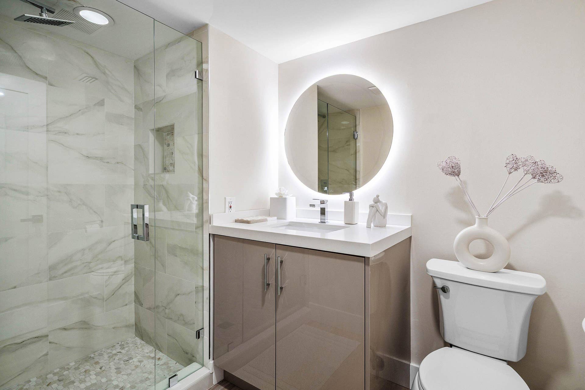 Bathroom featuring a glass-enclosed shower with stone-tile surround, pebble flooring, and integrated shower niche