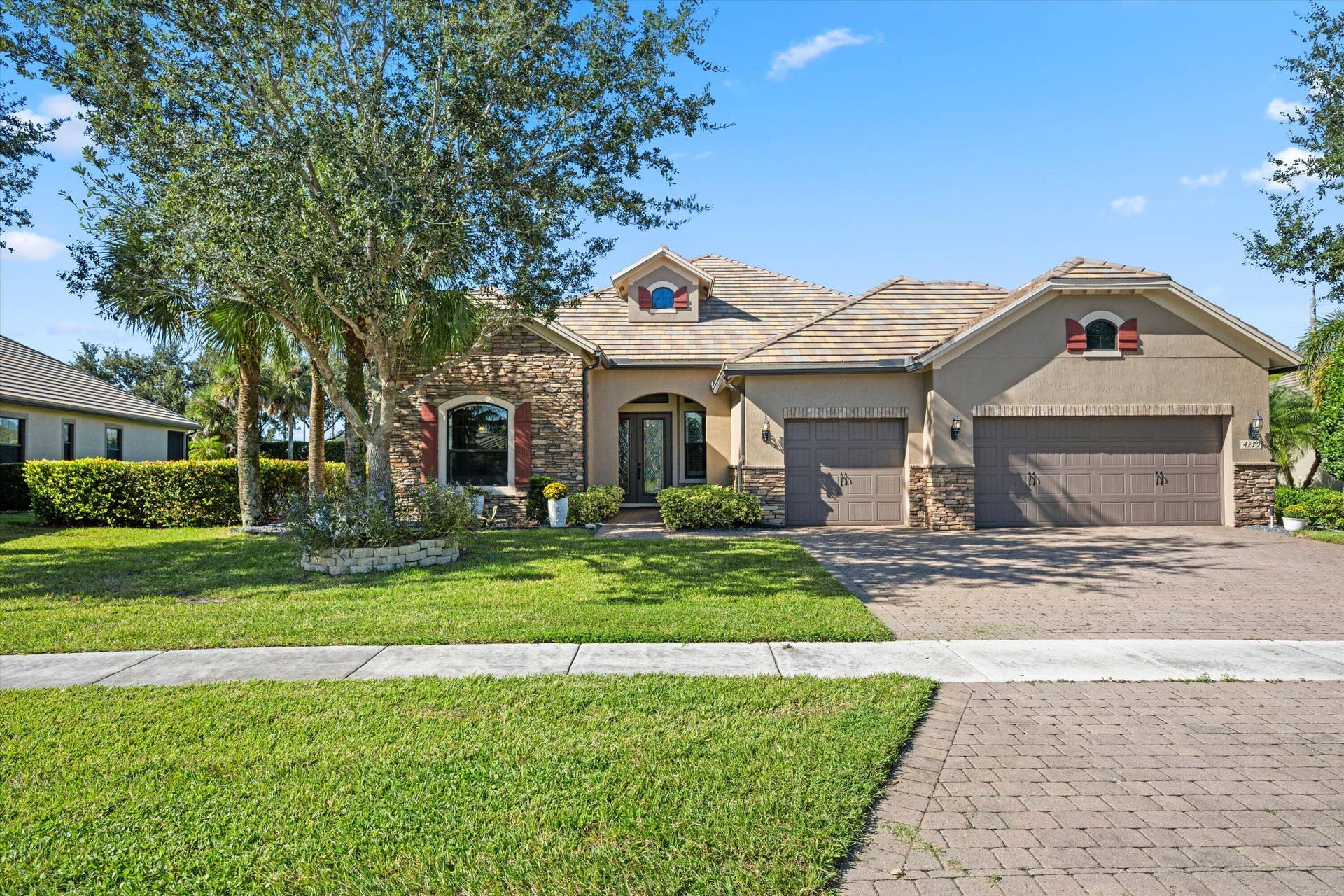 Residence featuring a stone and stucco facade, concrete tile roof, paved driveway, and arched entryway