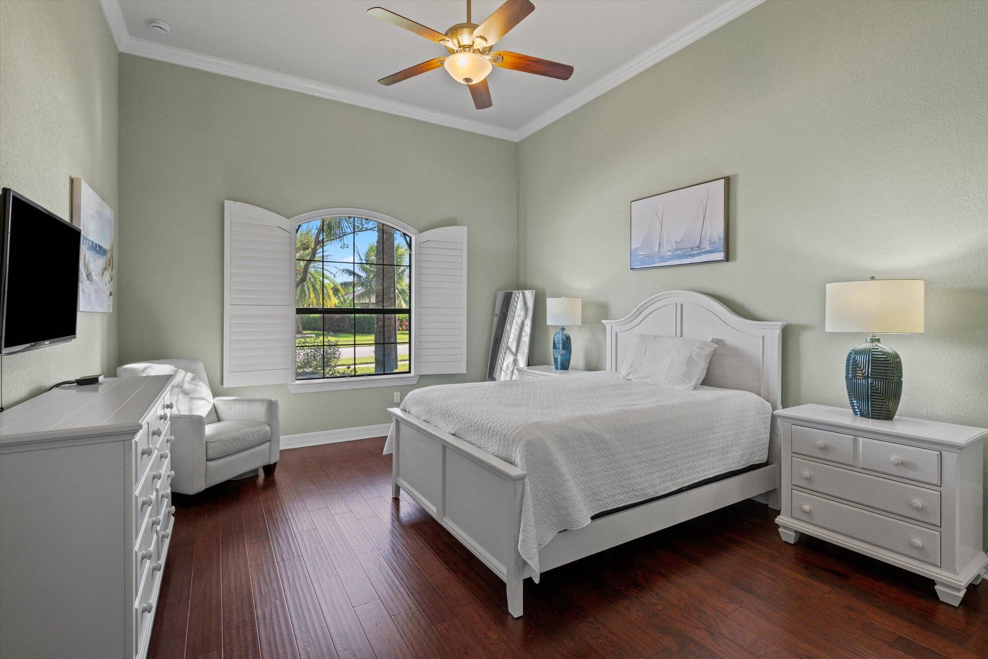 High ceilings with crown molding, wood-finish flooring, and an arched window featuring plantation shutters