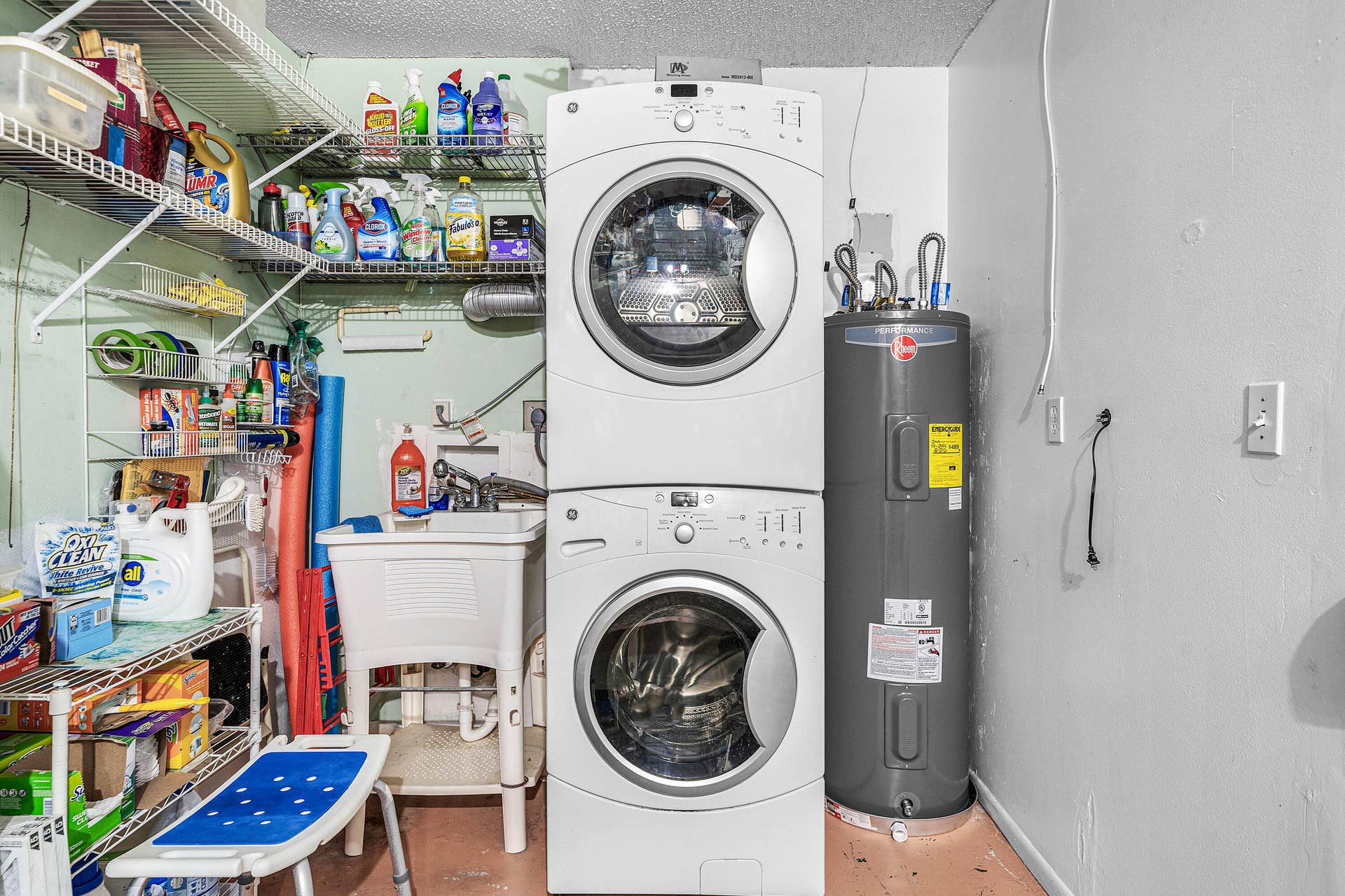 503 SW 29TH Avenue, Delray Beach, FL 33445 Laundry utility area featuring a stacked GE washer and dryer unit, a white basin utility sink, and installed metal wire shelving