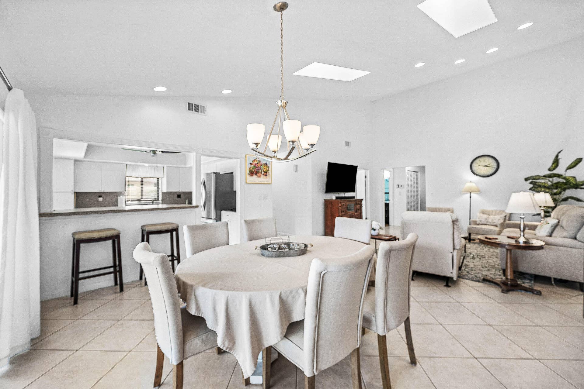 503 SW 29TH Avenue, Delray Beach, FL 33445 Open-concept living space featuring vaulted ceilings, recessed lighting, multiple skylights, large-format tile flooring, and a kitchen pass-through with a breakfast bar