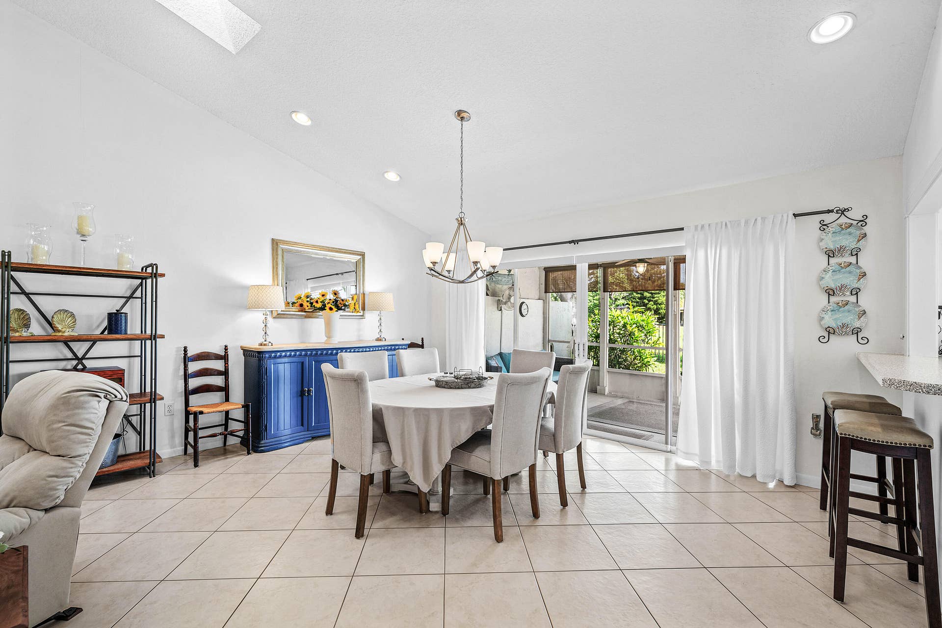 503 SW 29TH Avenue, Delray Beach, FL 33445 Vaulted ceilings, large-format ceramic tile flooring, recessed lighting, a multi-arm chandelier, and sliding glass doors