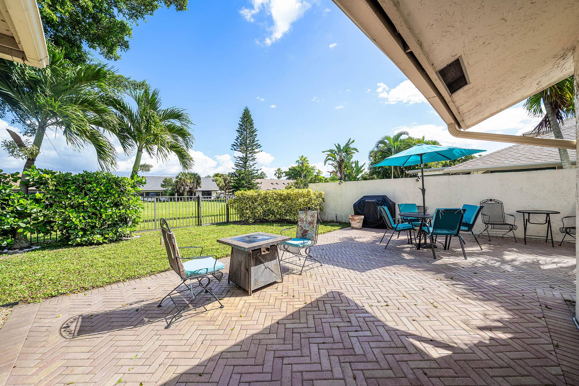 503 SW 29TH Avenue, Delray Beach, FL 33445 Covered patio with herringbone brick pavers, grass lawn, and perimeter fencing