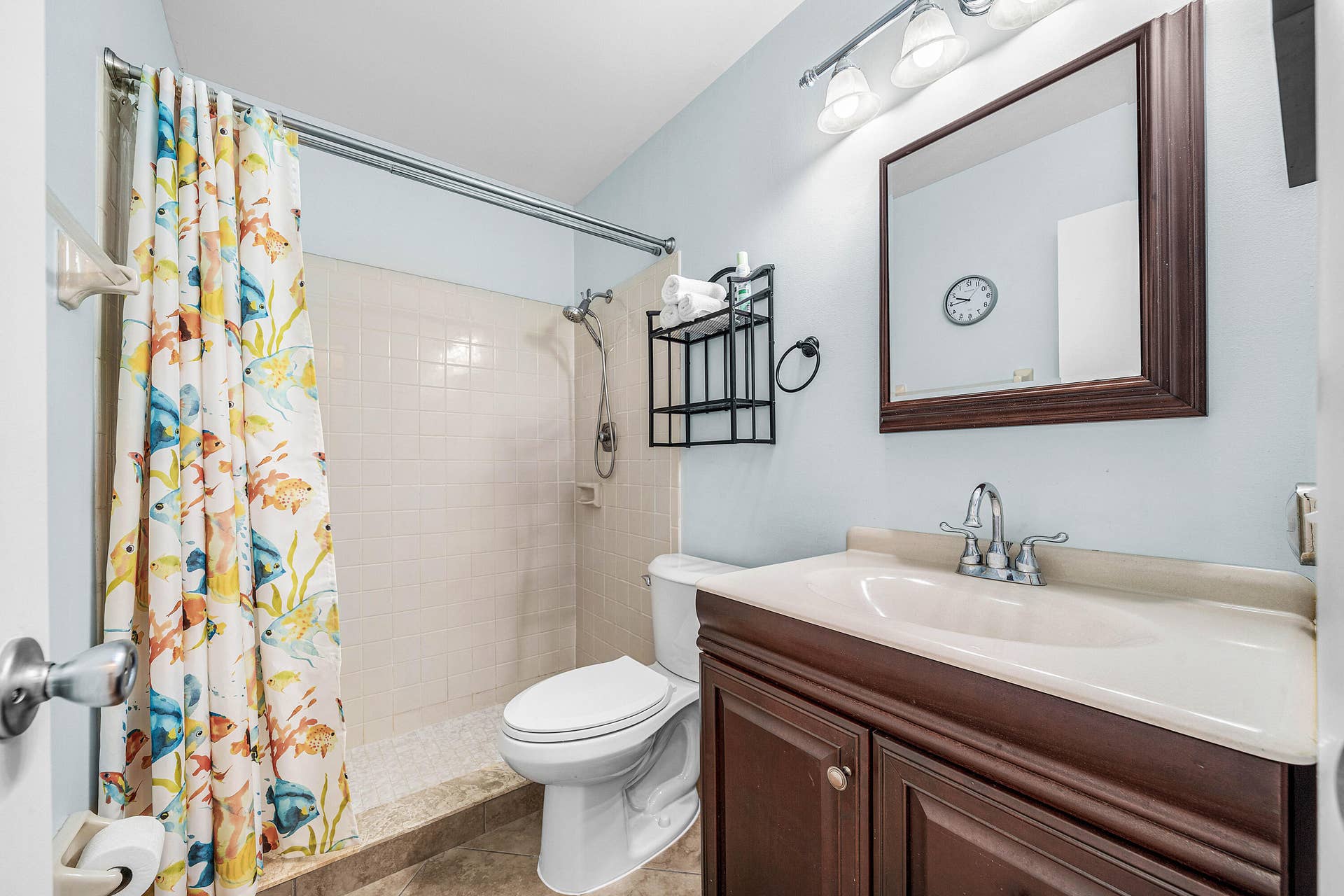 503 SW 29TH Avenue, Delray Beach, FL 33445 Bathroom featuring a vanity with an integrated countertop, dark wood-finish cabinetry, a framed wall mirror, a multi-light fixture, and a tiled shower stall with a handheld showerhead