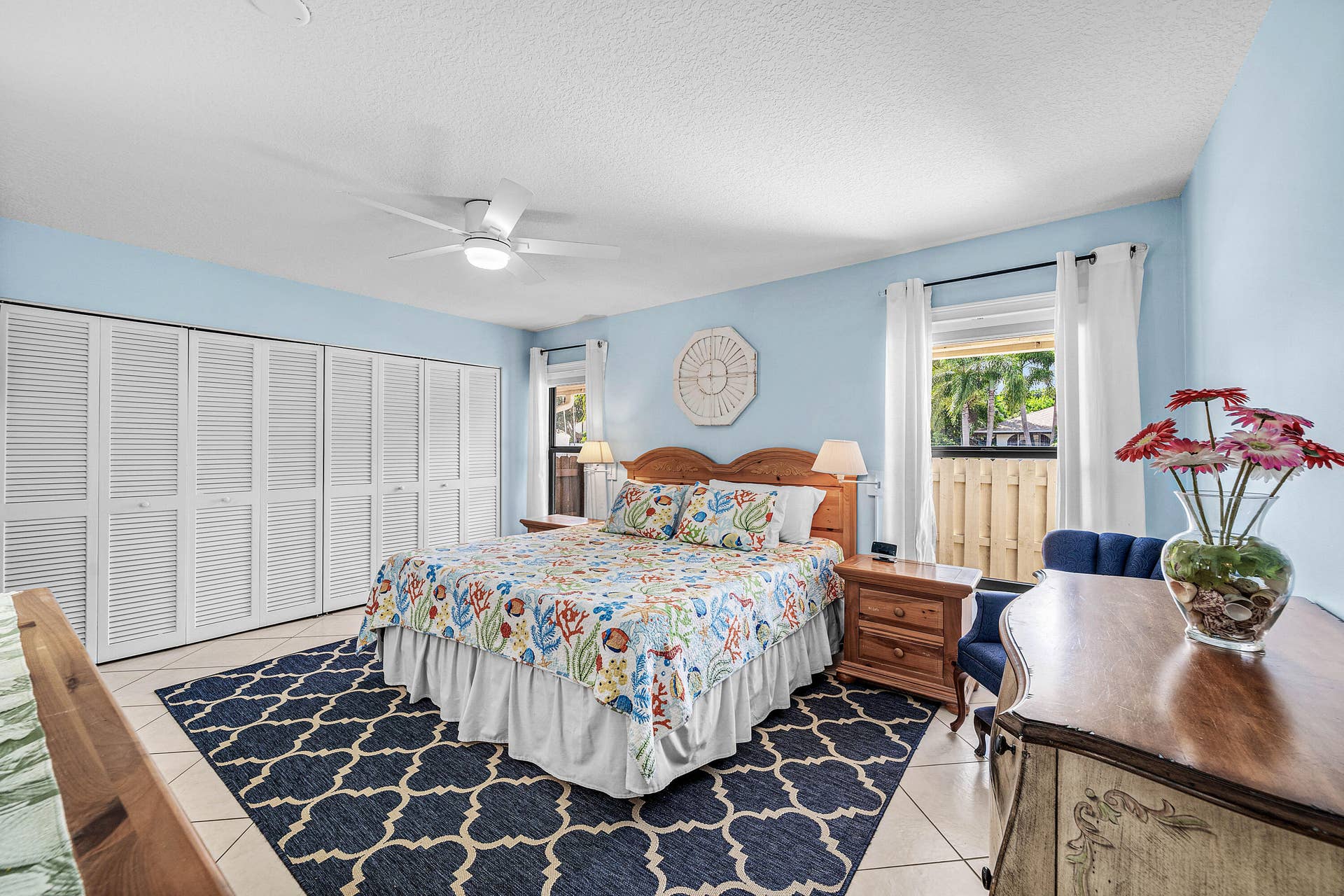 503 SW 29TH Avenue, Delray Beach, FL 33445 Spacious room featuring light-toned tile flooring, large louvered-style built-in closet doors, a white ceiling fan with integrated lighting, and dual windows with window treatments