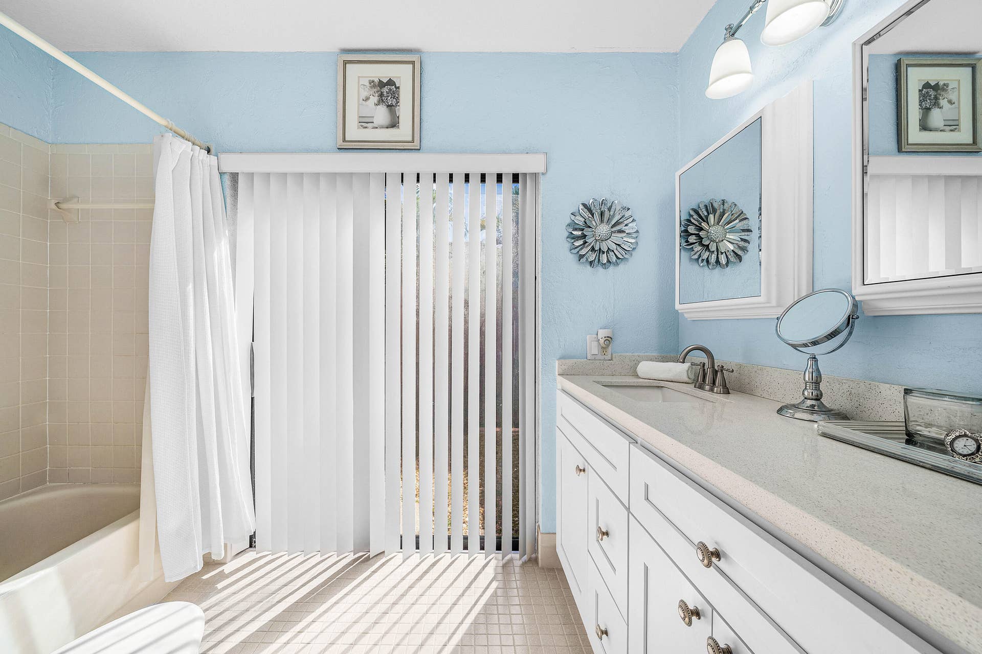 503 SW 29TH Avenue, Delray Beach, FL 33445 Bathroom featuring a double-sink vanity with stone-composite countertop, white cabinetry, integrated medicine cabinets, and sliding glass patio doors with vertical blinds