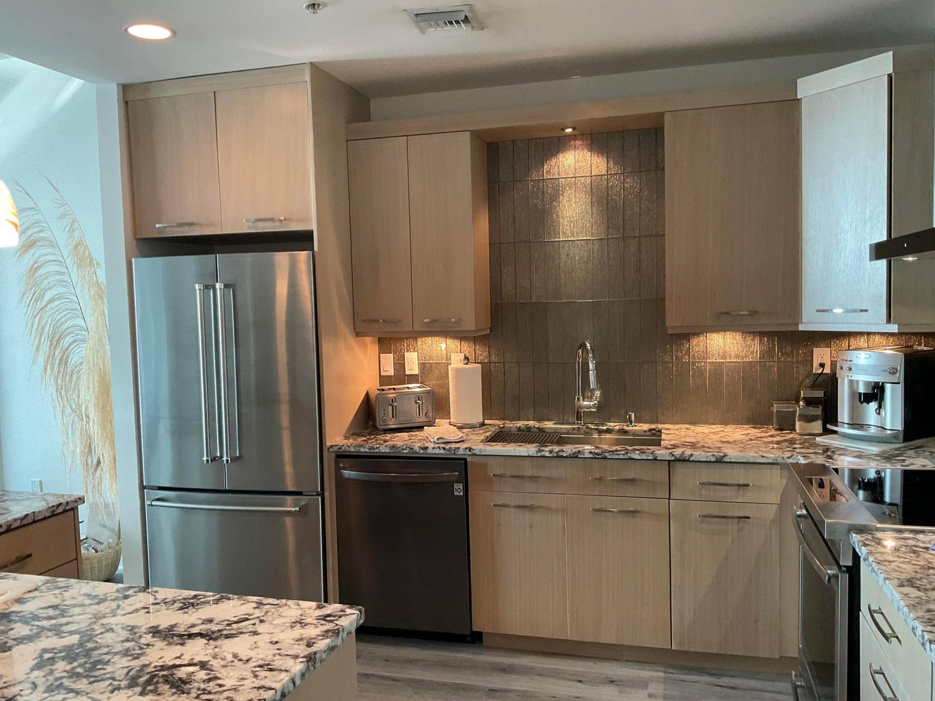 Kitchen with Custom marble counter tops and glass backsplash fully equipped with pans, dishes, cutlery, and small appliances.