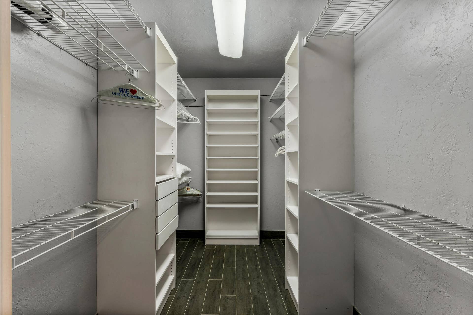 419 E Atlantic Avenue, Delray Beach, FL 33483 Walk-in closet featuring white built-in shelving, integrated storage drawers, wire shelving racks, and wood-finish tile flooring