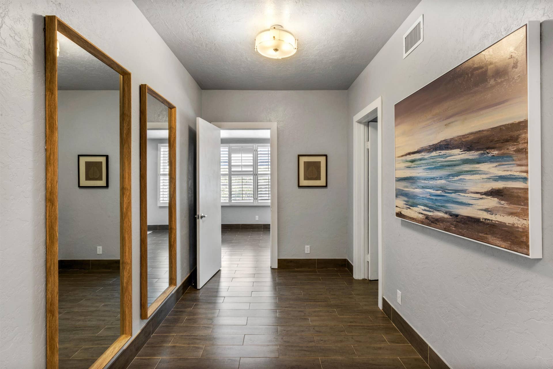 419 E Atlantic Avenue, Delray Beach, FL 33483 Hallway featuring tile flooring, two full-length wall-mounted mirrors with wood-finish frames, and a flush-mount dome light fixture