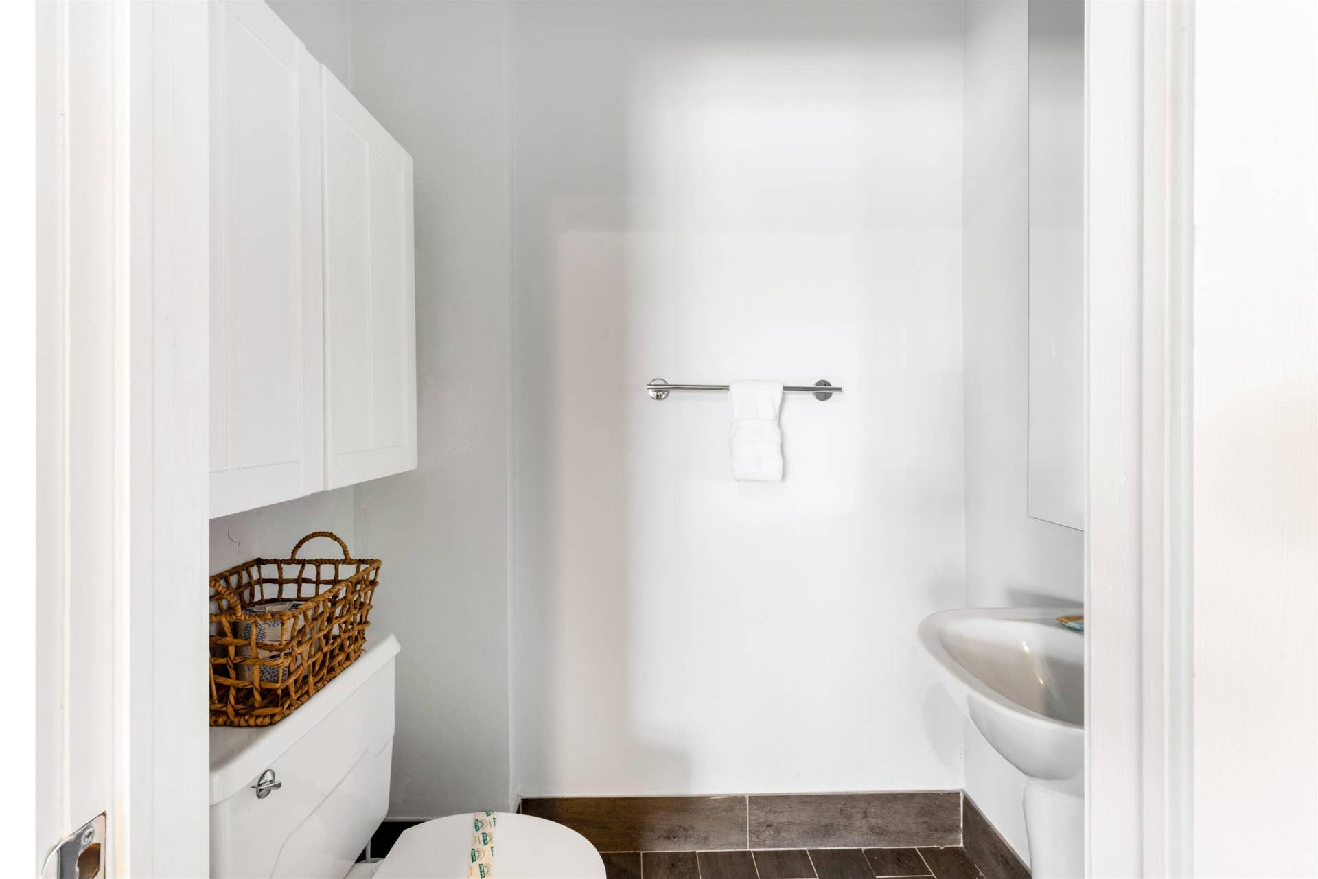 419 E Atlantic Avenue, Delray Beach, FL 33483 Wall-mounted white cabinetry, white pedestal sink, polished chrome faucet hardware, wall-mounted towel bar, and dark-toned floor tiling