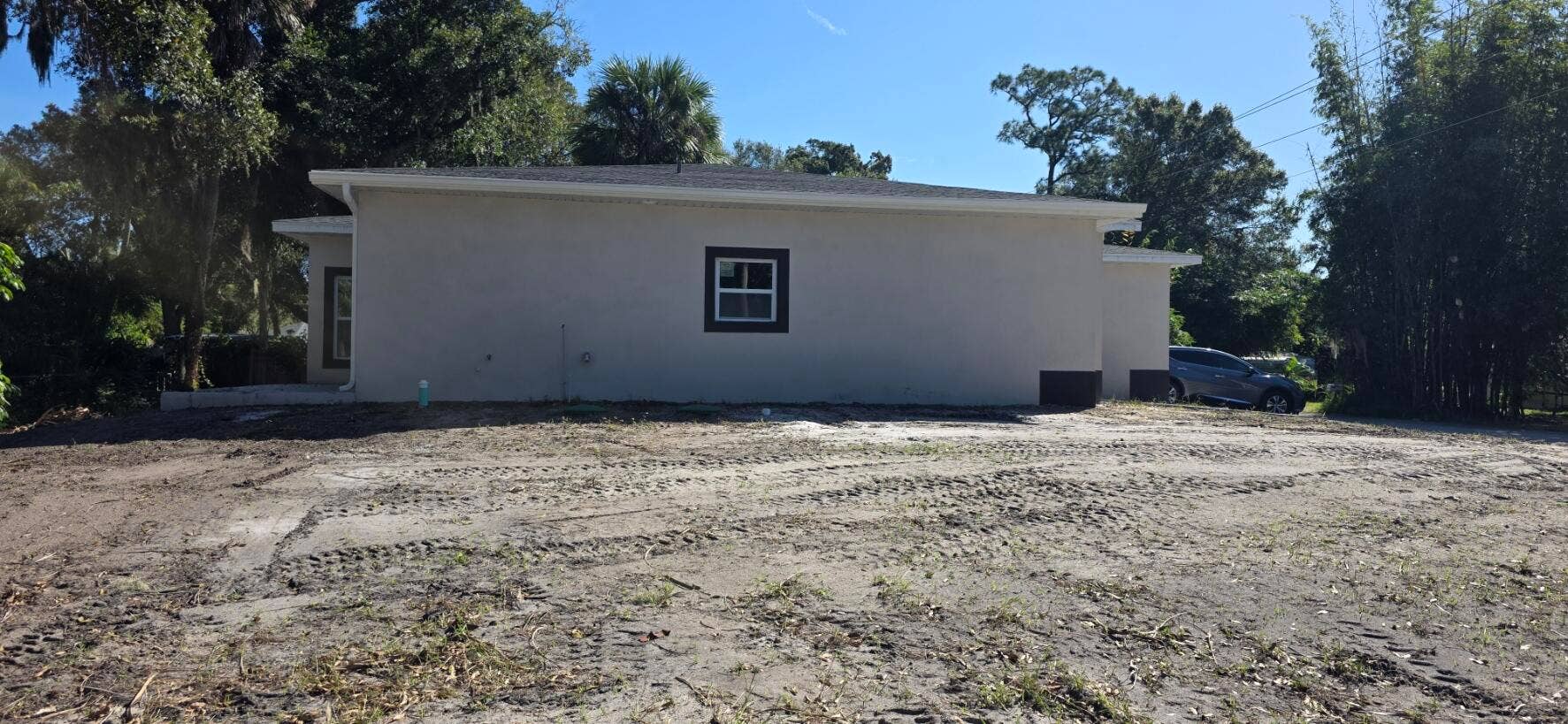 Stucco exterior featuring a hipped roofline, dark-trimmed window frames, and foundation-level accents