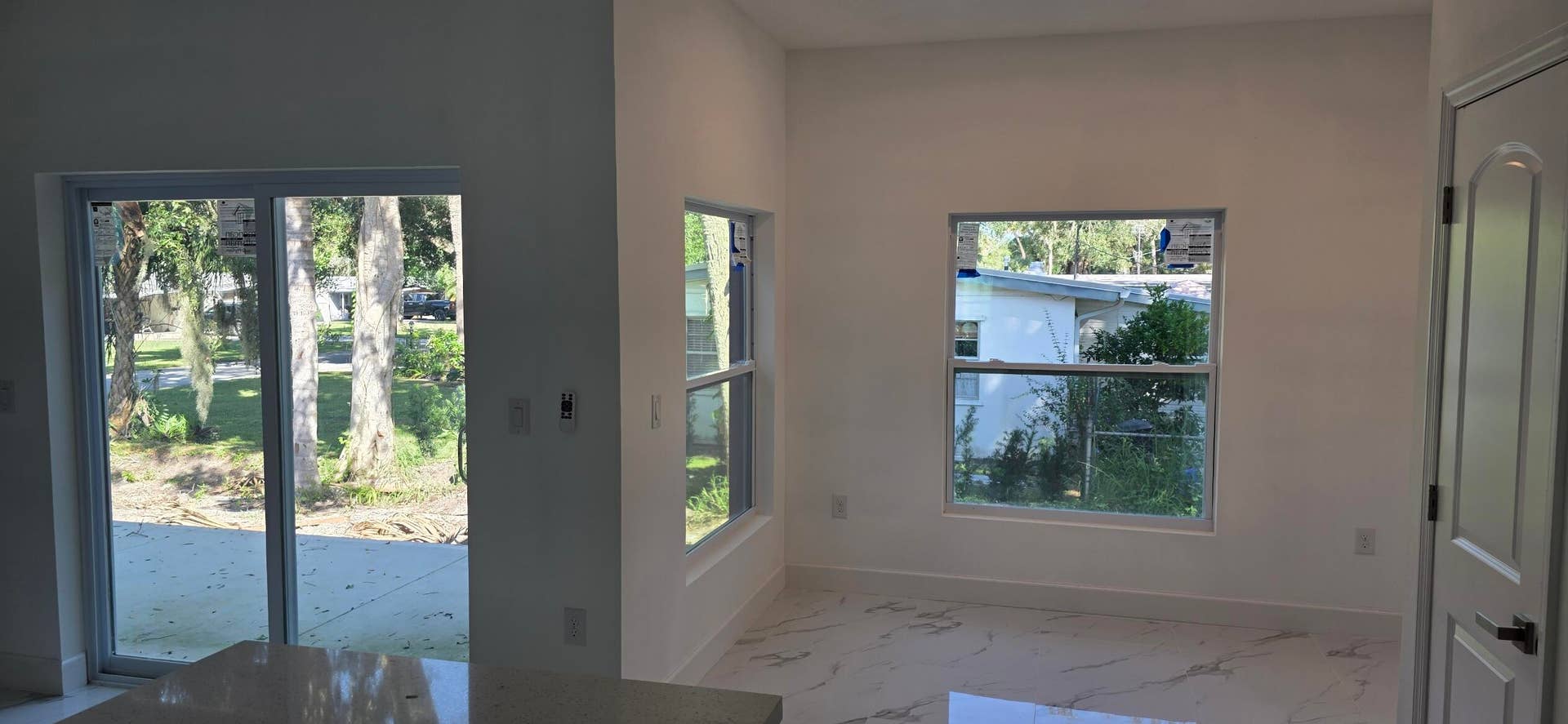 Interior area featuring large-format tile flooring, double-pane windows, sliding glass door, and solid-core panel door