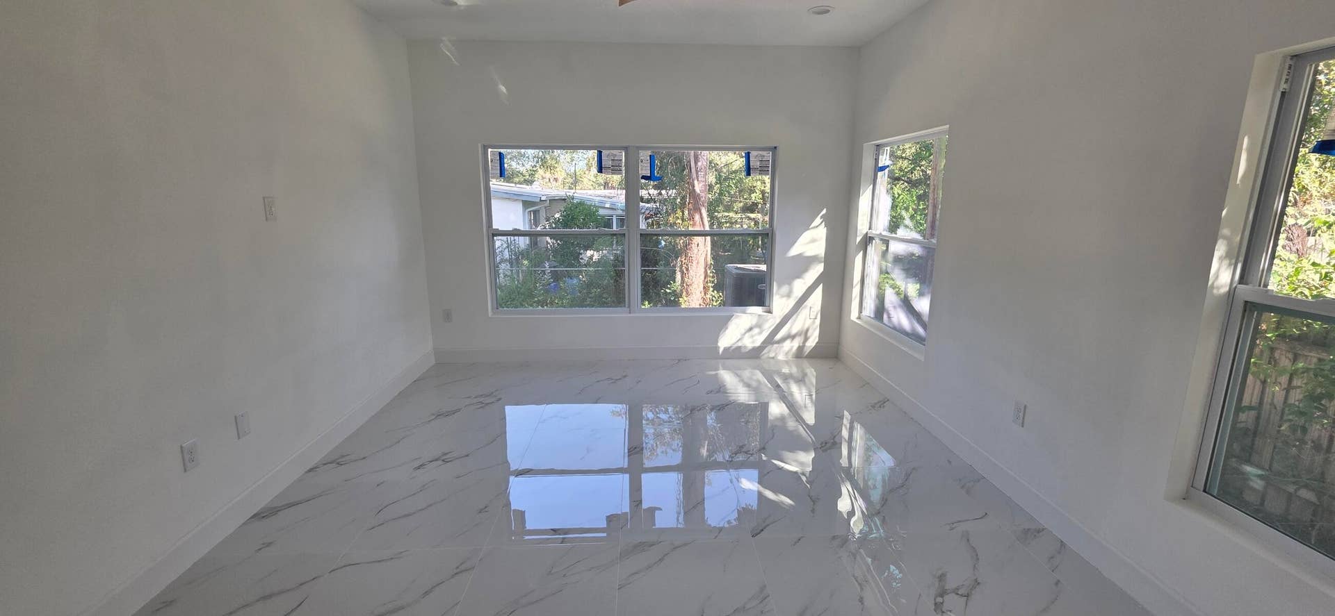 Polished white tile flooring with gray veining, multiple multi-pane windows, and recessed ceiling lighting