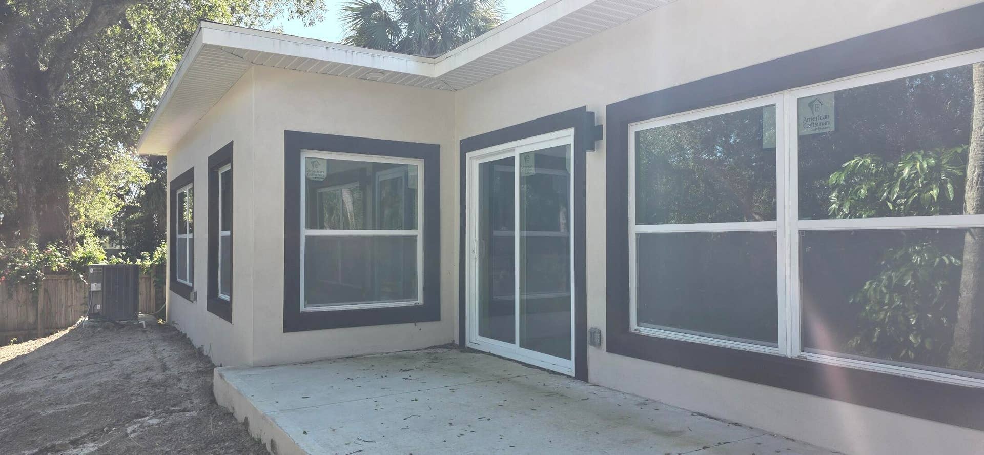 Stucco exterior featuring dark-trimmed windows, sliding glass door, and a concrete patio