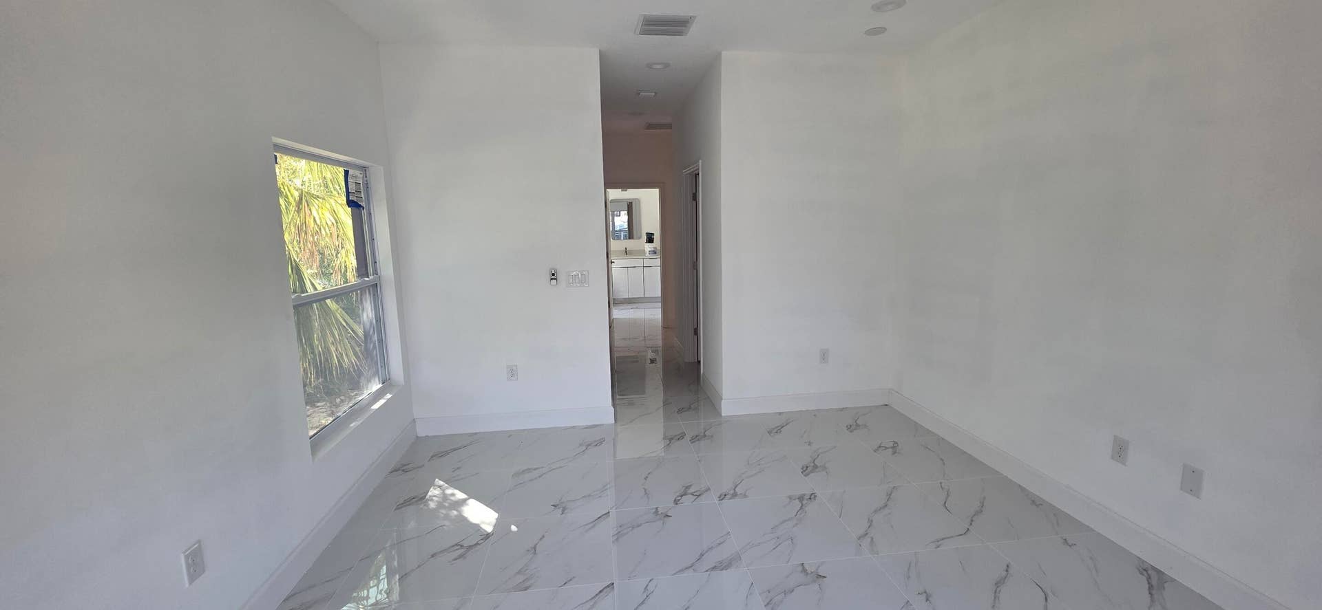 Large-format tile flooring with veined detailing, recessed ceiling lighting, and a single-pane window