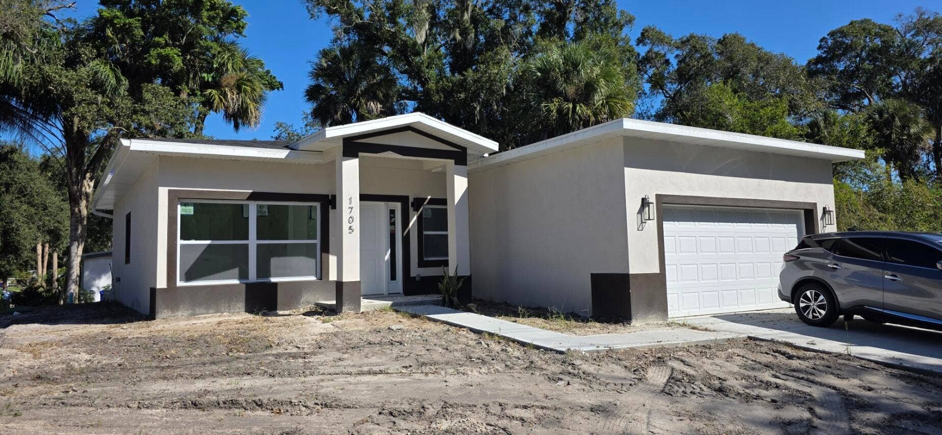 Single-story residence featuring a stucco exterior, covered entryway, attached garage, and multi-pane windows