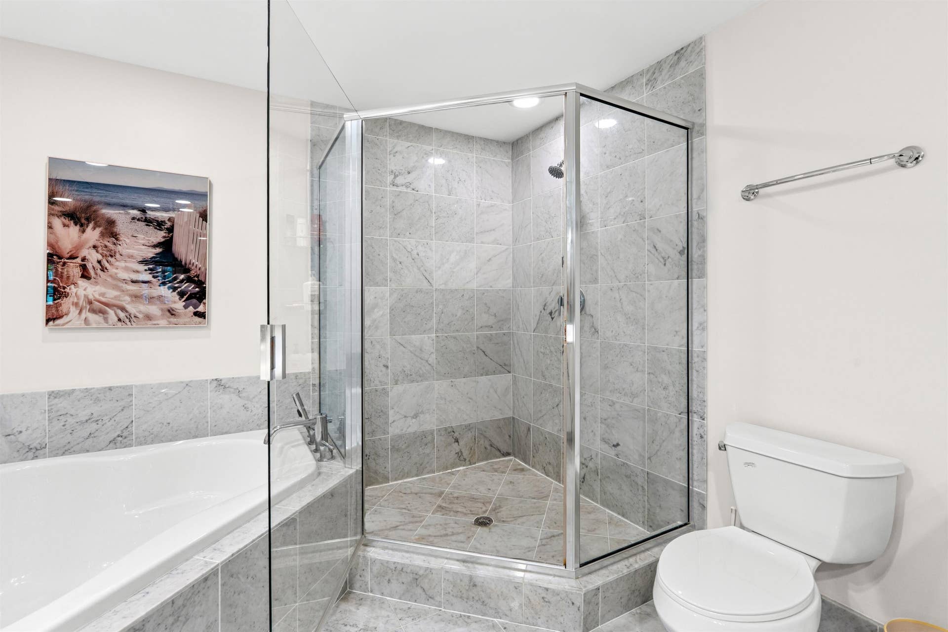 Corner shower enclosure featuring full-height stone tile surround, chrome-finish hardware, glass door, and soaking tub with stone tile deck
