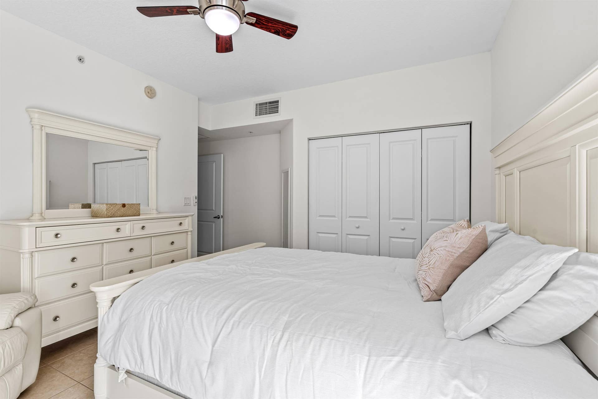 Room featuring neutral paint, tile flooring, built-in bi-fold closet doors, and a ceiling fan with integrated lighting