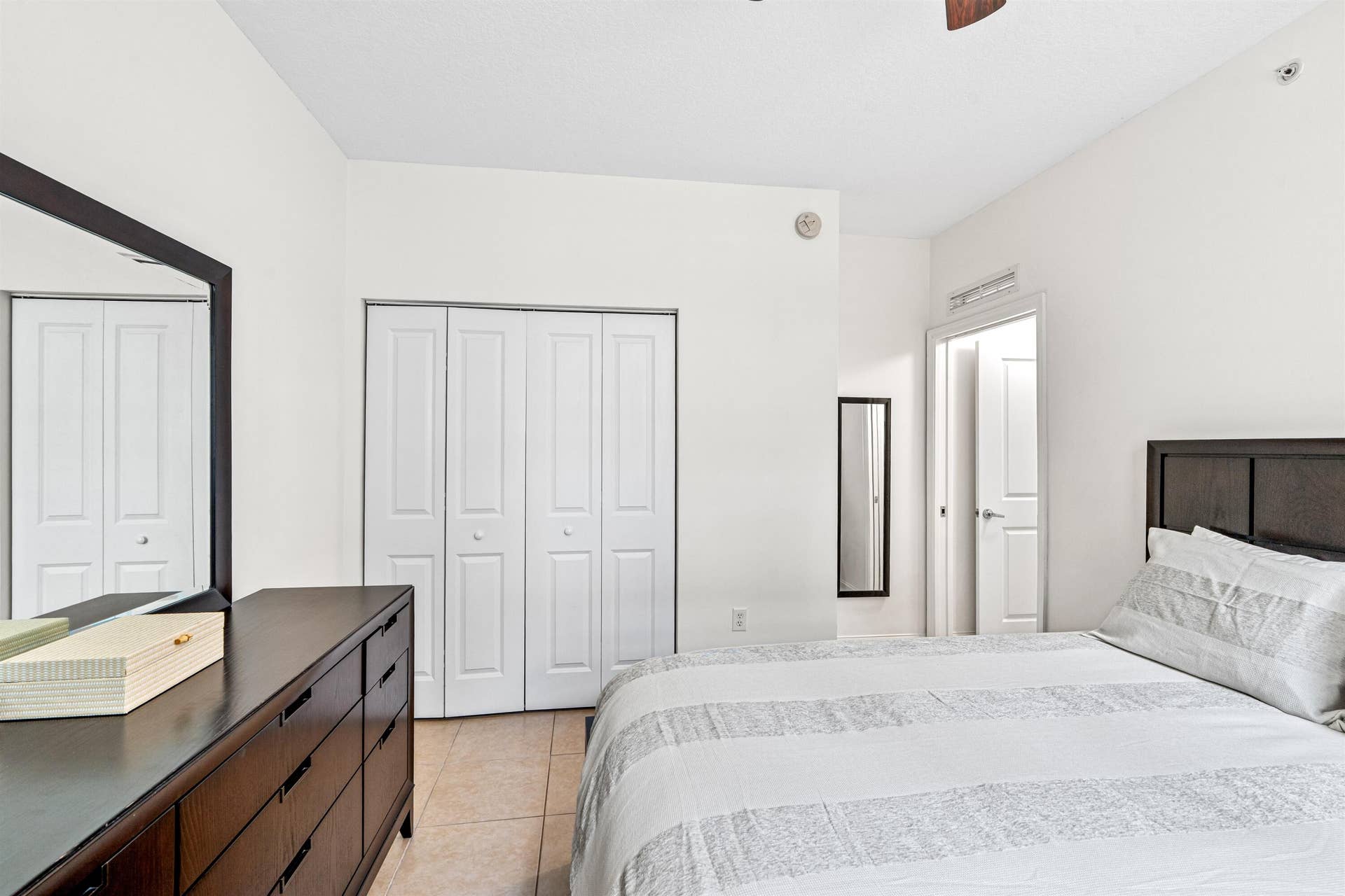 Neutral-toned interior featuring tiled flooring, a built-in bi-fold closet, and a ceiling fan