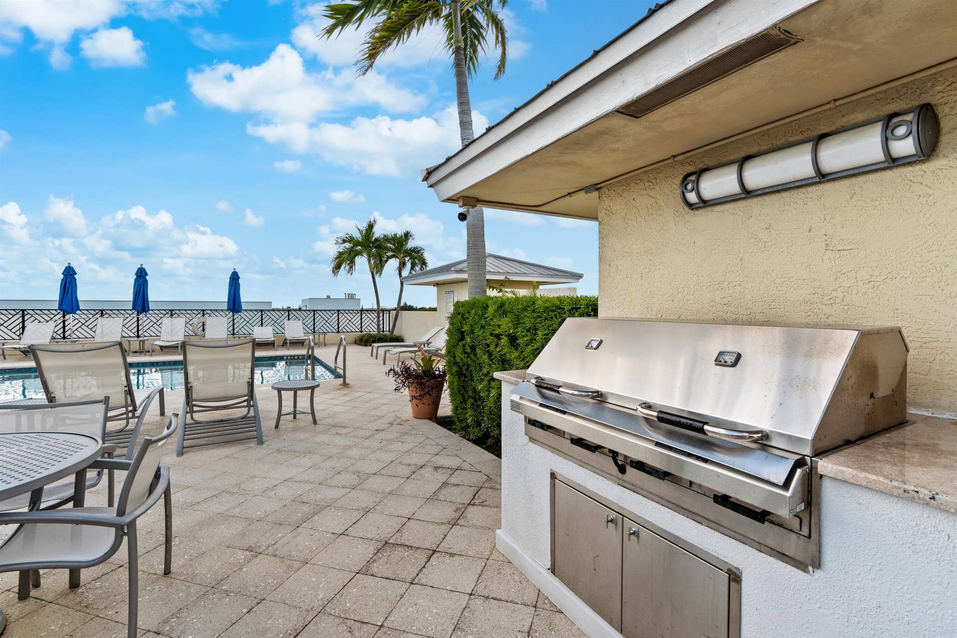 Outdoor terrace featuring a built-in stainless steel grill, stone countertop, tiled flooring, and swimming pool