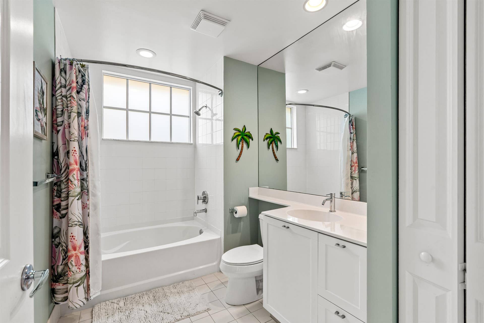 Bathroom featuring a white vanity cabinet with an integrated sink, full-width wall mirror, tub and shower combination with tile surround, grid-patterned window, and recessed lighting