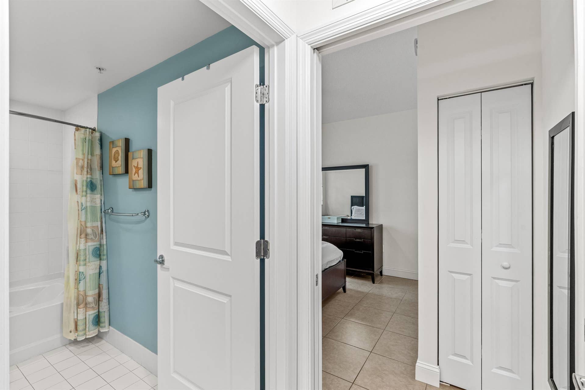 Bathroom featuring a tile-surround bathtub and a bifold closet door, complete with neutral tile flooring