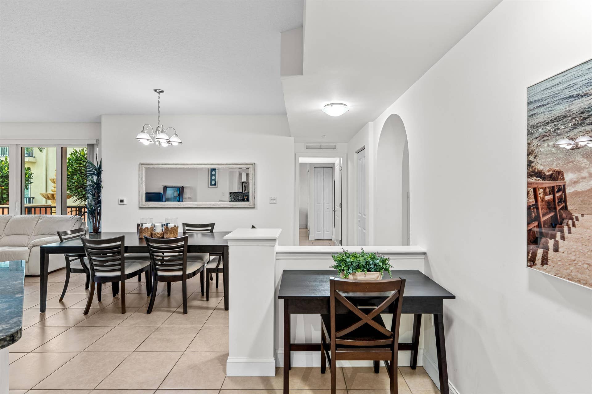 Open-concept interior featuring neutral tile flooring, arched wall detailing, and a multi-light chandelier fixture