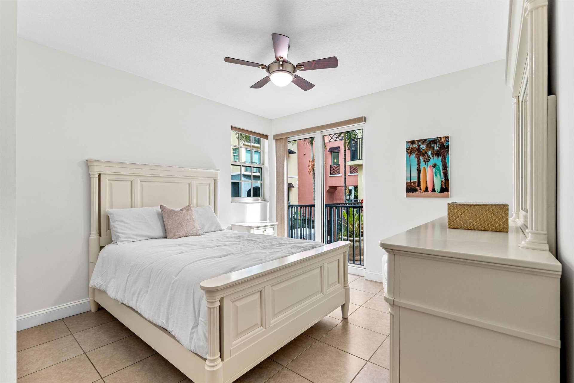 Neutral-toned tile flooring, ceiling fan with integrated lighting, and sliding glass doors featuring a metal balcony railing