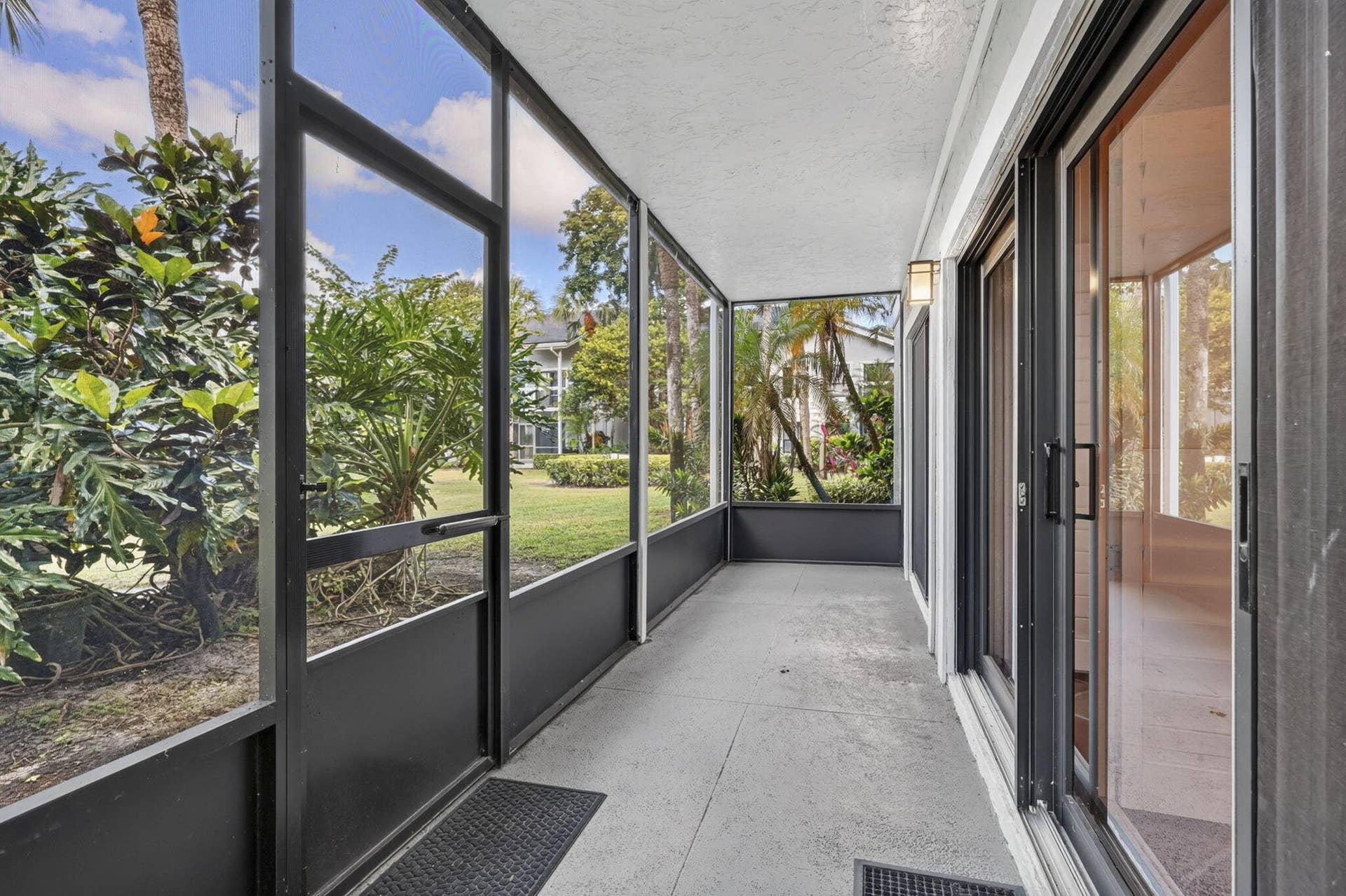 Screen-enclosed porch featuring concrete flooring, aluminum framing, and multi-panel sliding glass doors