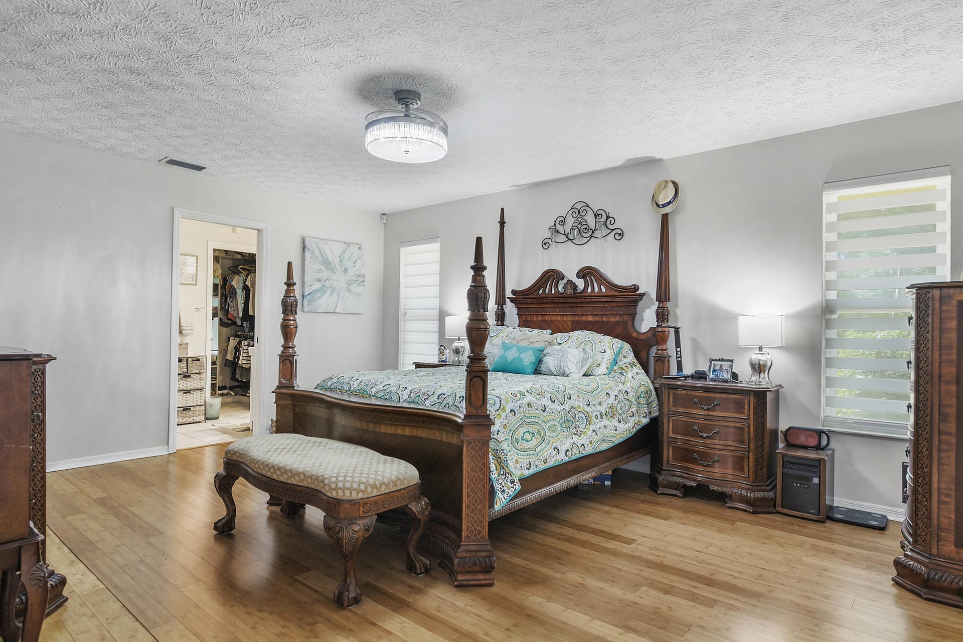 3098 SE BUR Street, Port St Lucie, FL 34952 Inviting primary suite featuring bamboo beautiful flooring, stylish window treatments, two walk-in closets, and a brand-new ceiling fan with lighting.