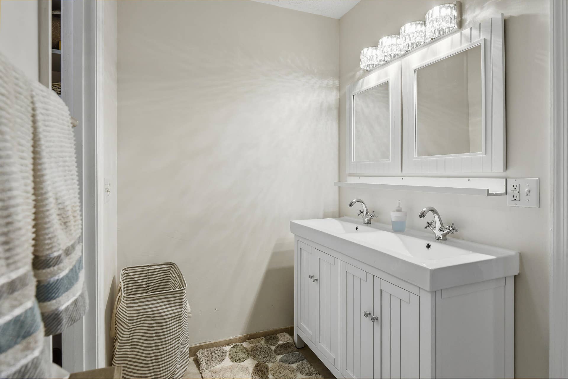 3098 SE BUR Street, Port St Lucie, FL 34952 Bright primary bathroom featuring a double-sink vanity, decorative mirrors, updated lighting, and convenient access to two separate walk-in closets.