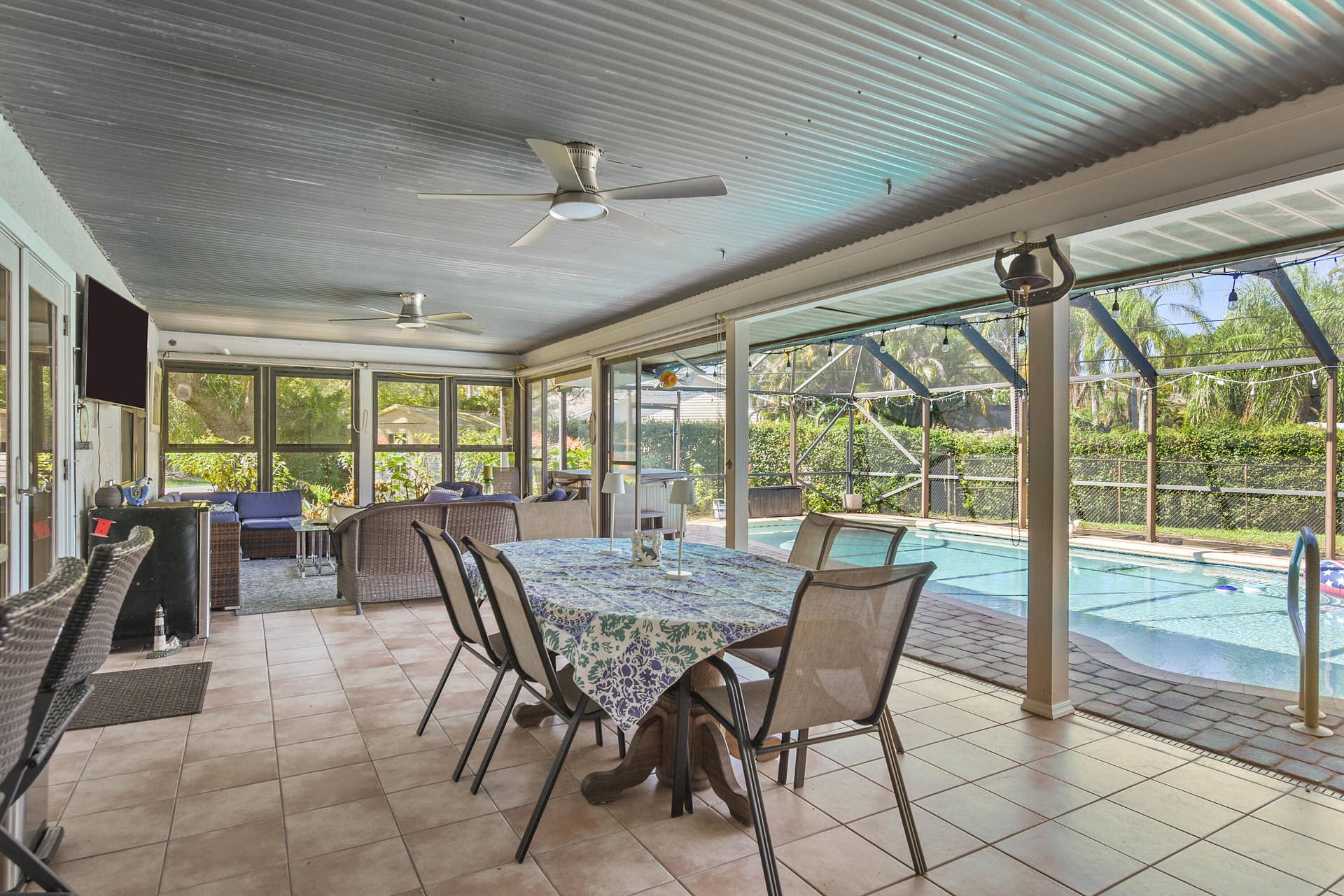 3098 SE BUR Street, Port St Lucie, FL 34952 Enjoy the best of indoor-outdoor living! This inviting enclosed lanai features dining and lounging areas, ceiling fans, and beautiful views of the pool. Perfect for entertaining or simply unwinding!