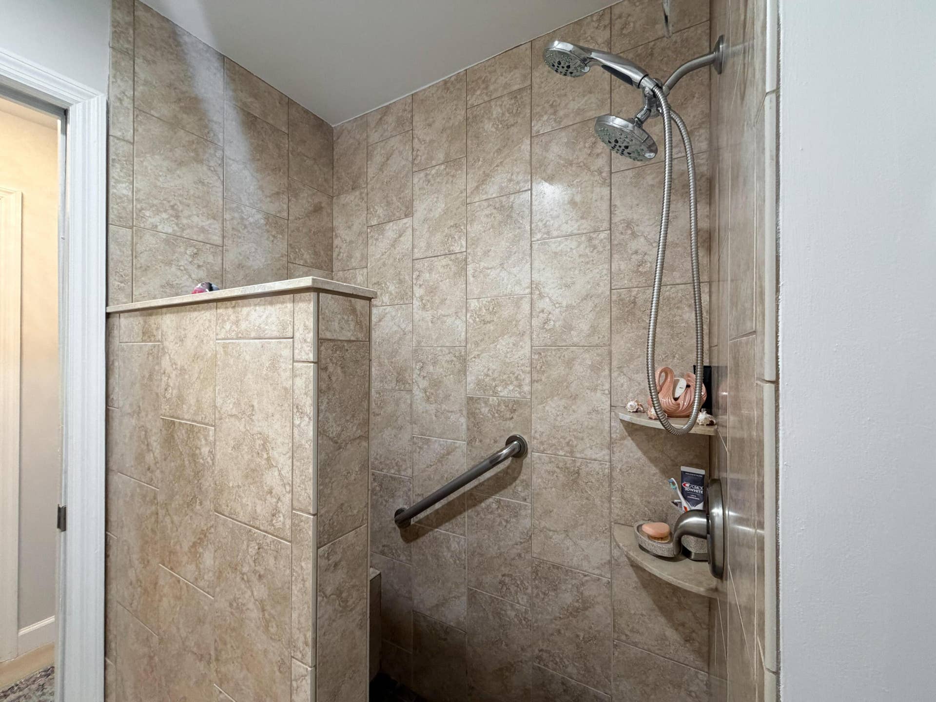 3098 SE BUR Street, Port St Lucie, FL 34952 Enjoy a walk-in shower featuring floor-to-ceiling tile, a convenient built-in bench, handheld showerhead, and grab bar for added comfort.