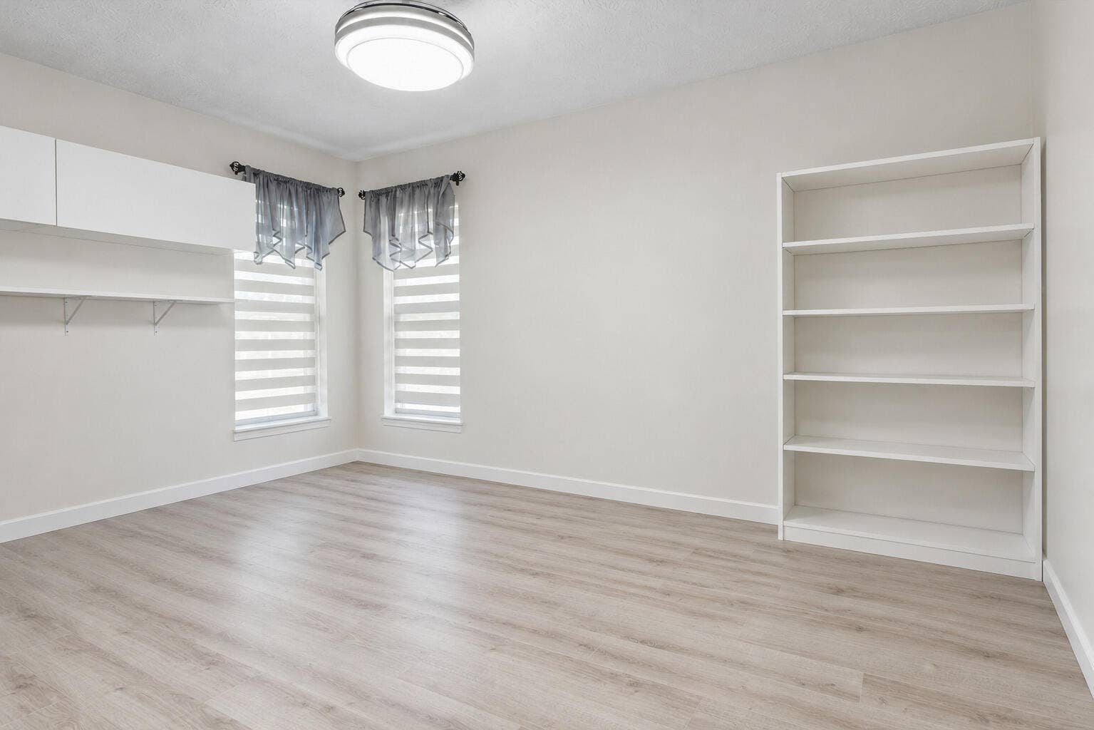3098 SE BUR Street, Port St Lucie, FL 34952 Bedroom 4 shown without furniture, highlighting beautiful flooring, built-in shelving, stylish window treatments, and flexibility for use as a bedroom, home office, or hobby room.