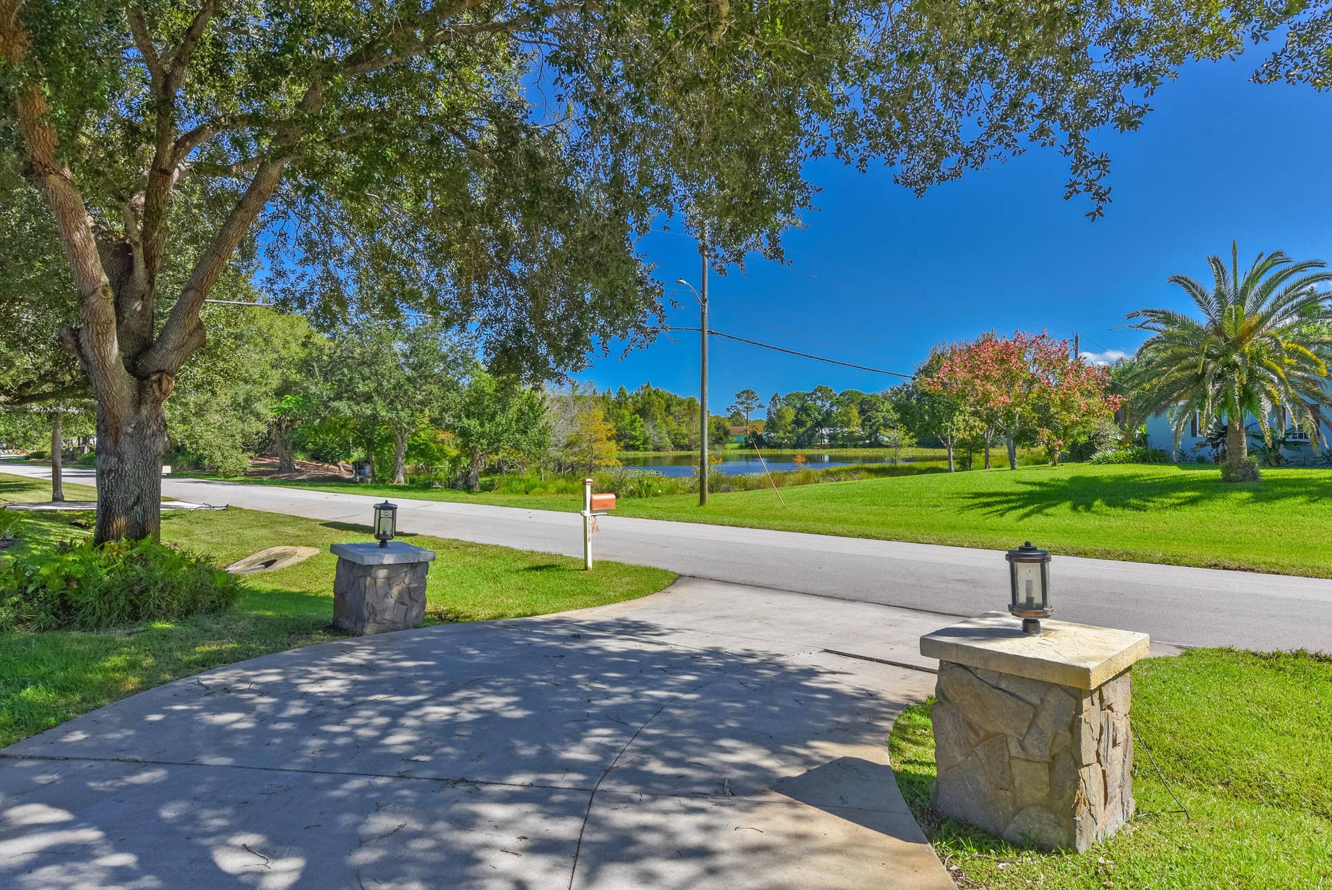3098 SE BUR Street, Port St Lucie, FL 34952 Enjoy a spacious driveway framed by decorative stone pillars, mature shade trees, lush landscaping