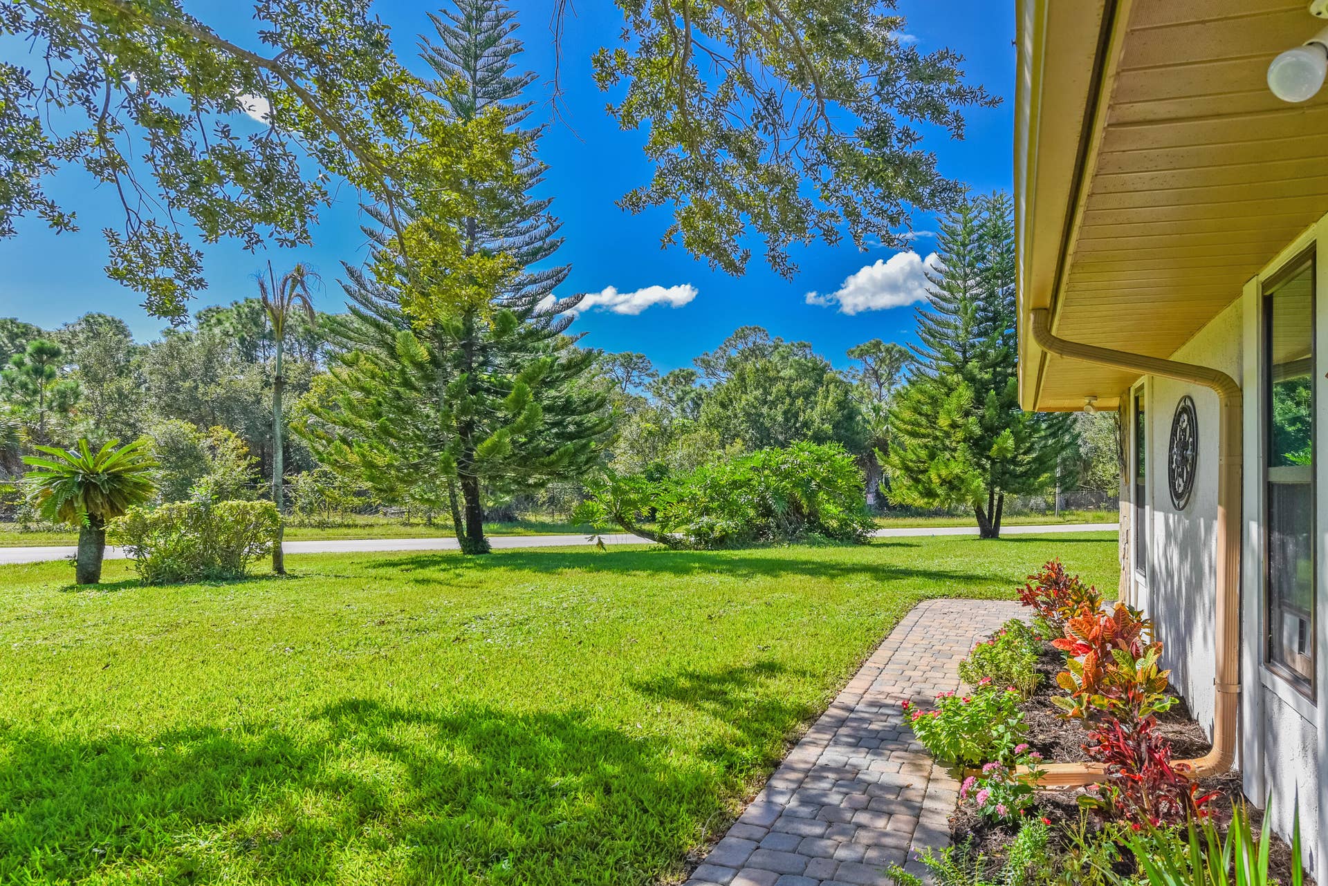 3098 SE BUR Street, Port St Lucie, FL 34952 Enjoy the expansive green lawn, mature trees, colorful tropical plantings, and charming paver walkway