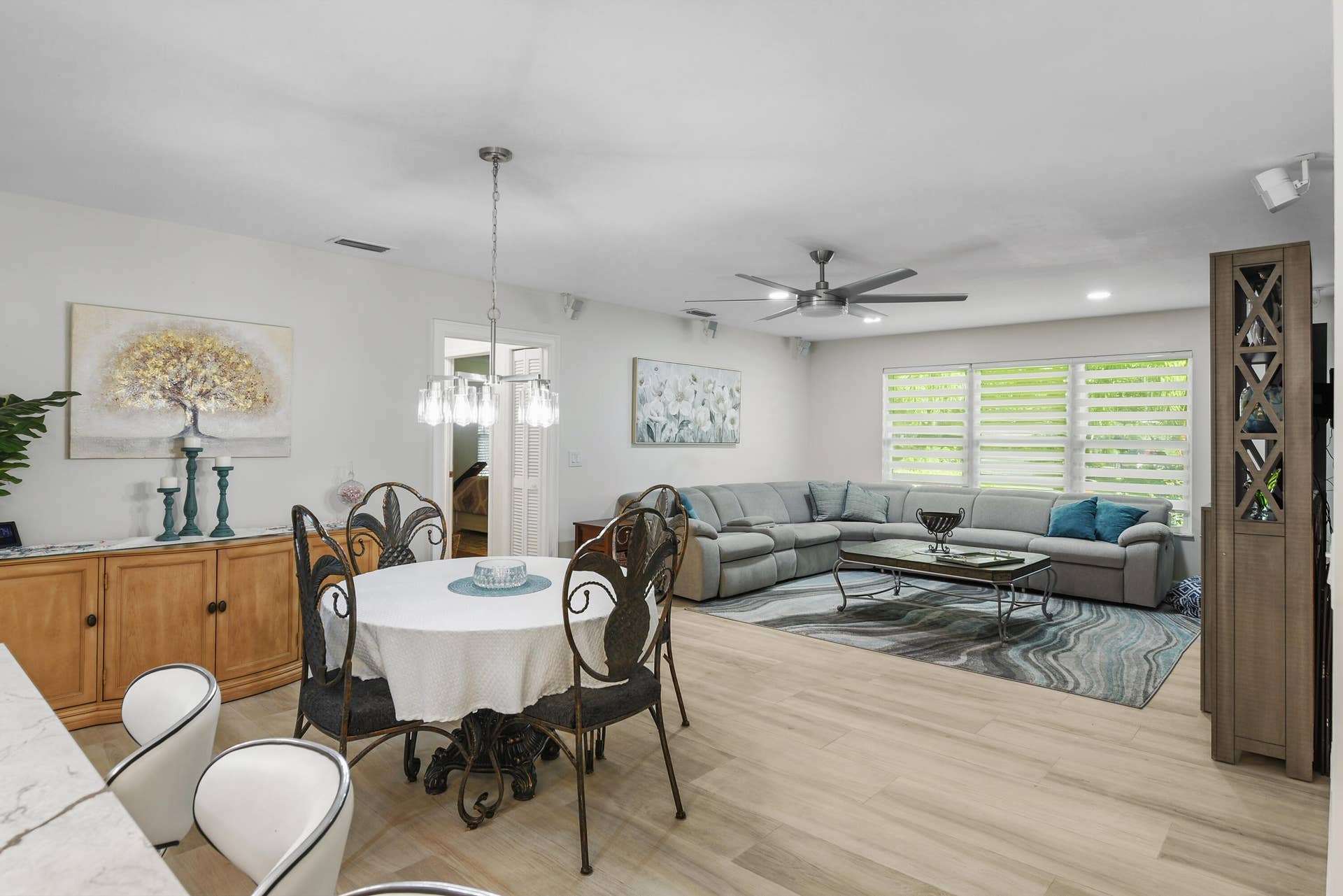 3098 SE BUR Street, Port St Lucie, FL 34952 Bright, spacious family room flows seamlessly into the casual dining area and kitchen. Beautiful wide-plank flooring, modern ceiling fan, and stylish window treatments create an inviting space for relaxing and entertaining!