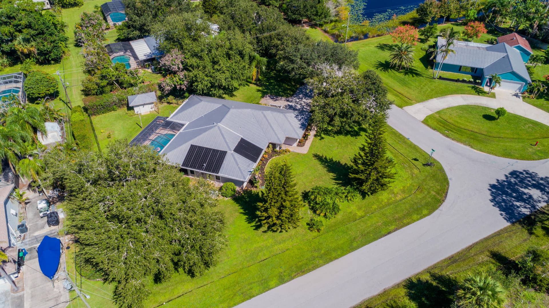 3098 SE BUR Street, Port St Lucie, FL 34952 Aerial view showcasing the metal roof, beautifully landscaped .49-acre lot, screened pool, and additional paved parking ideal for your boat or recreational toys. No HOA!