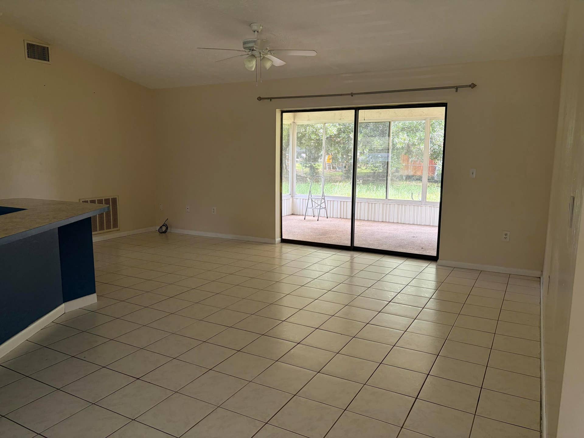 Open floor plan featuring tile flooring, ceiling fan, and sliding glass doors leading to a screened porch area